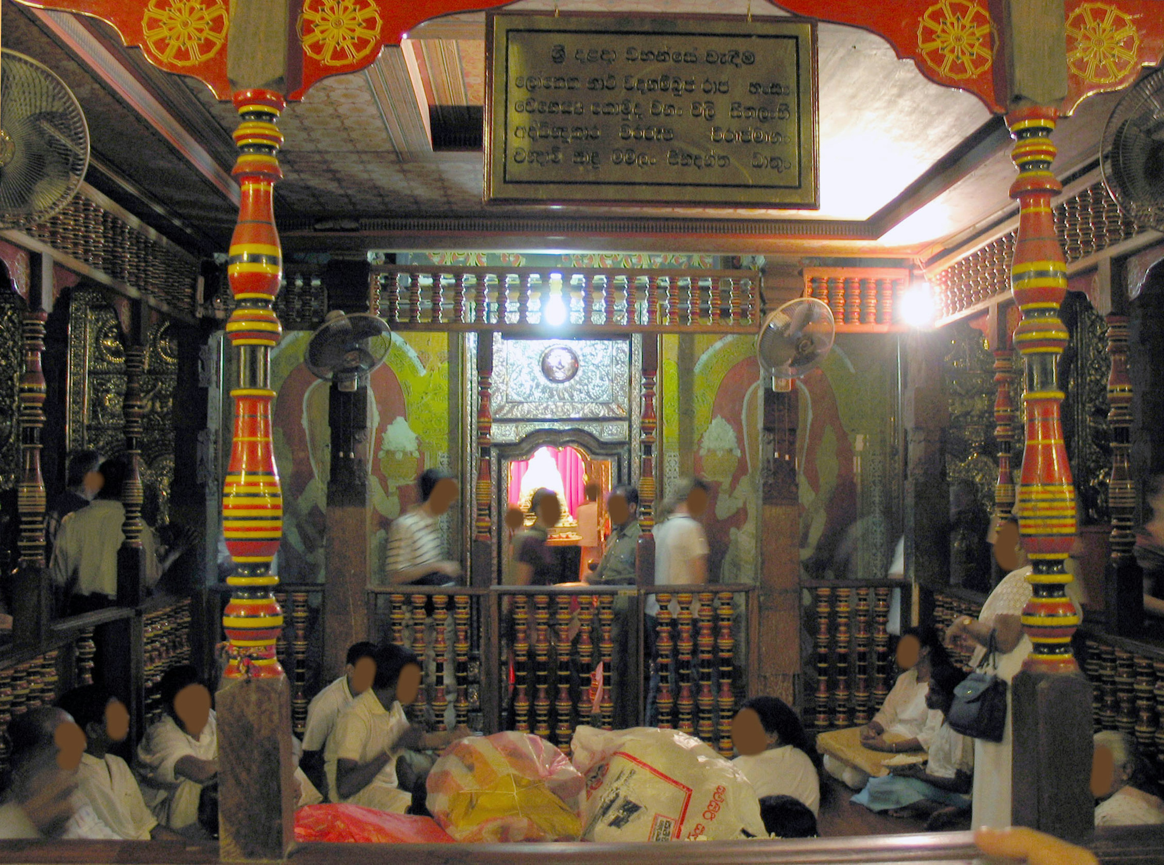 Interior of a colorful temple with people gathered and intricate decorations