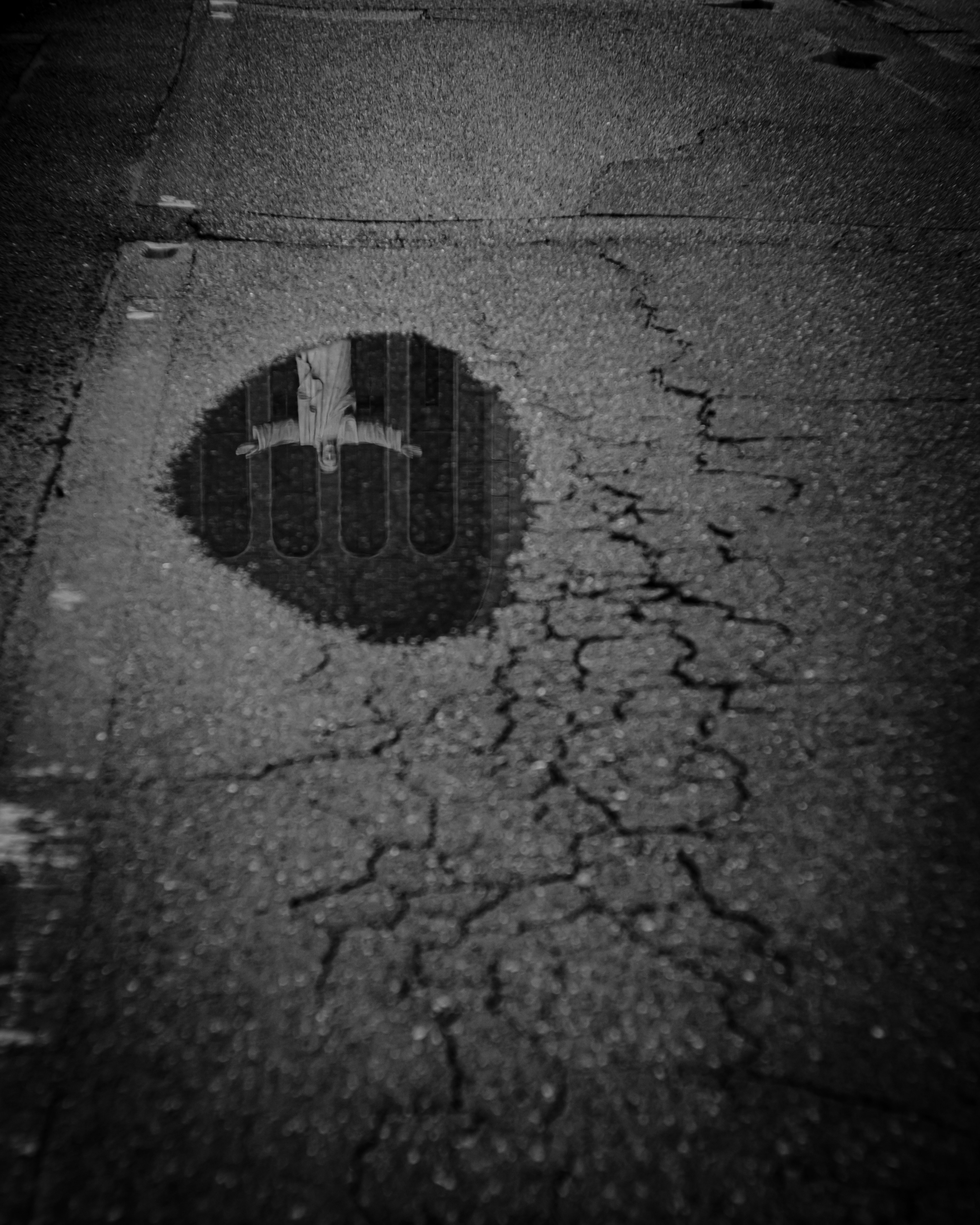 Reflejo de un edificio en un charco sobre un pavimento agrietado