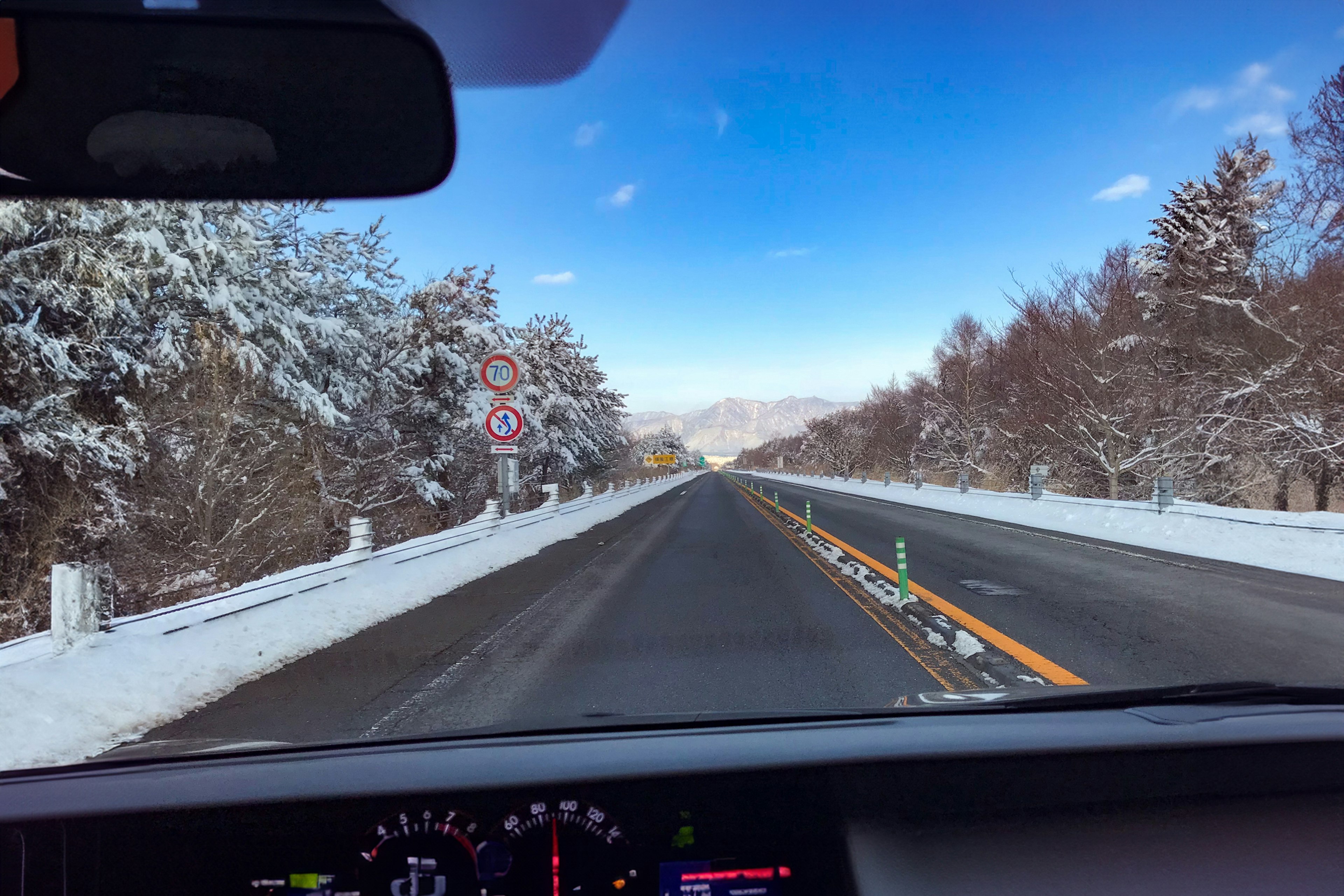 Carretera nevada con árboles y cielo azul