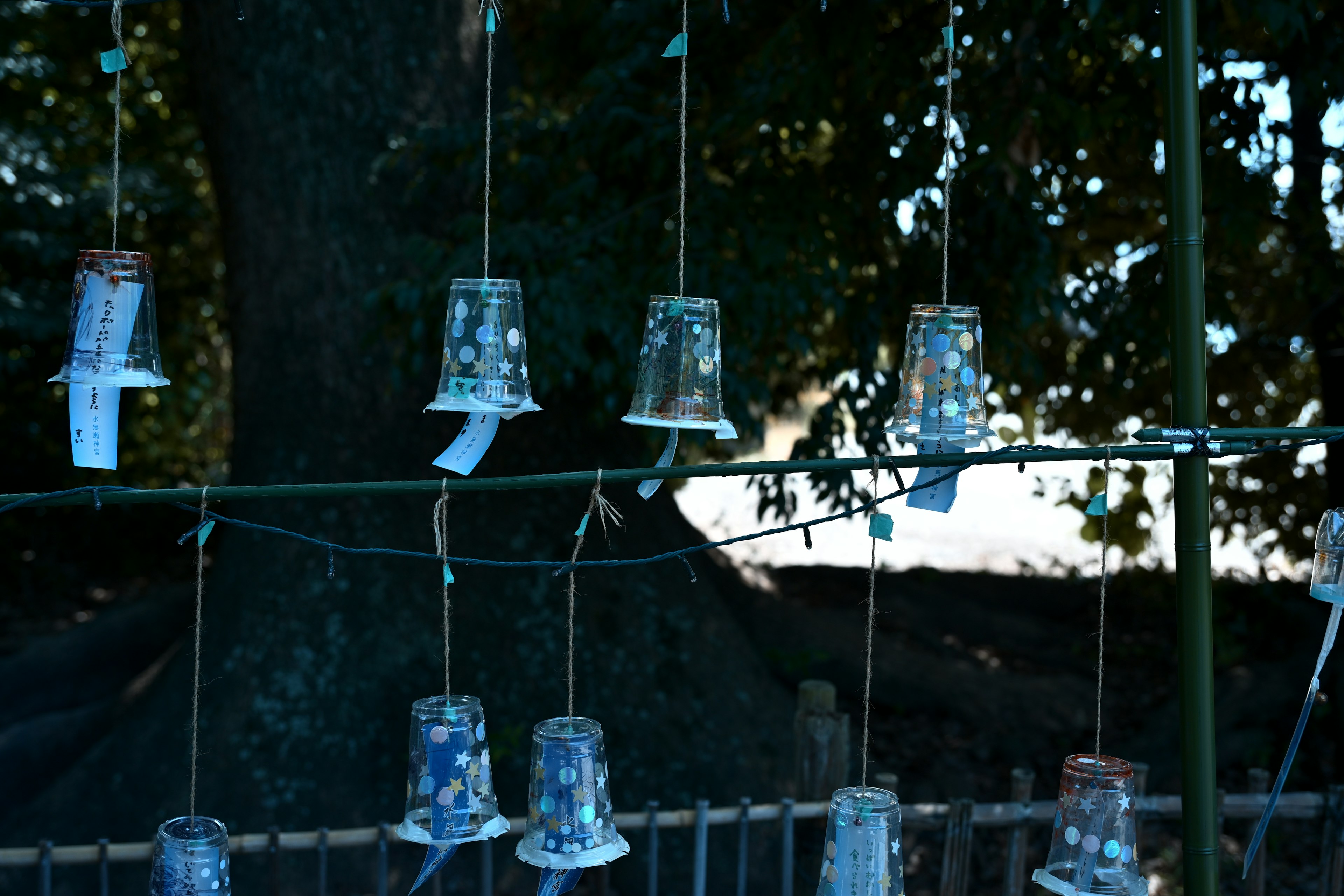 Des tasses en verre suspendues par des cordes dans un cadre extérieur paisible