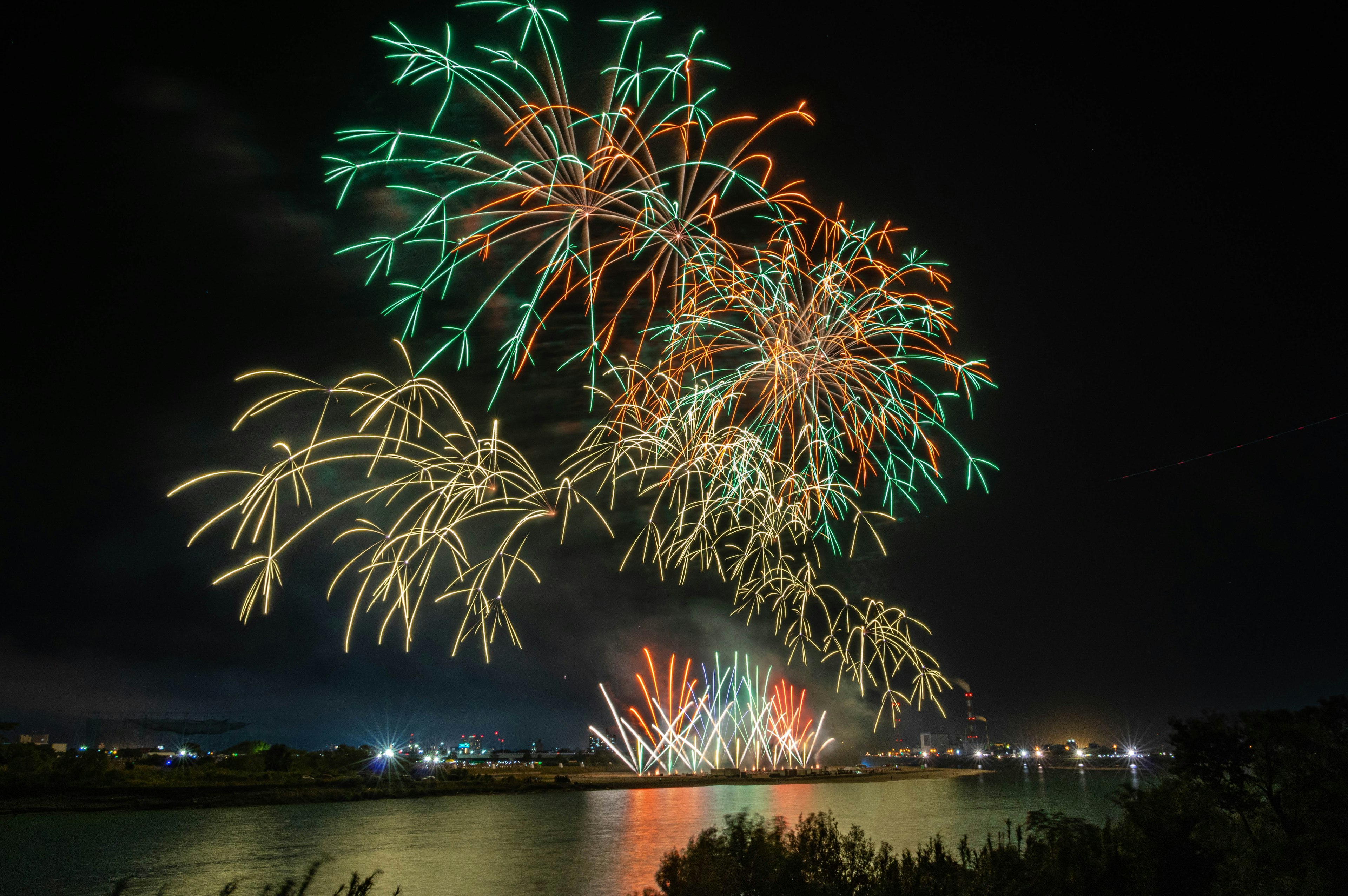 Spectacle de feux d'artifice colorés dans le ciel nocturne se reflétant sur l'eau