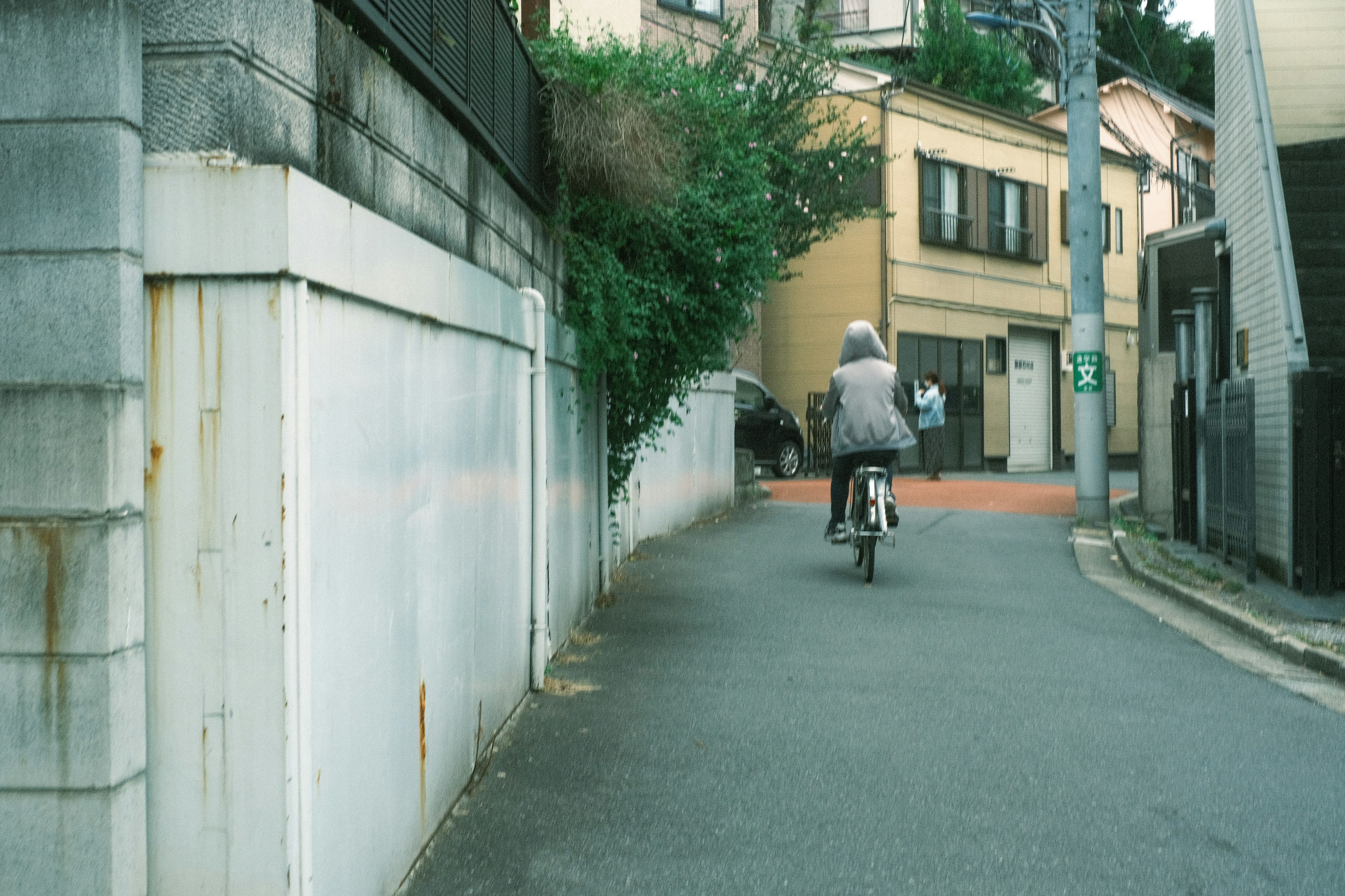 自転車に乗る人物が狭い路地を進む風景