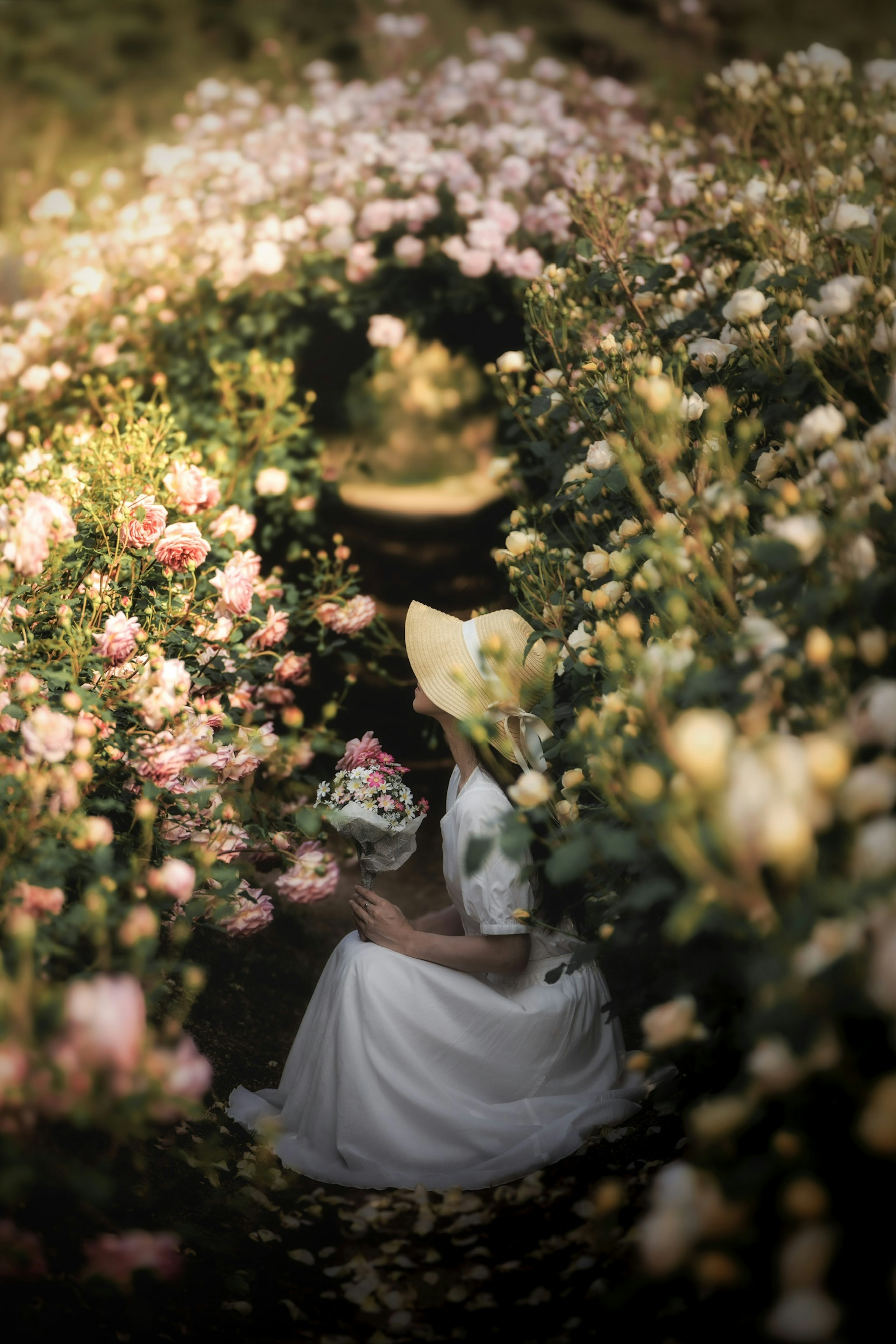 Mujer con vestido blanco sosteniendo un ramo rodeada de flores en flor