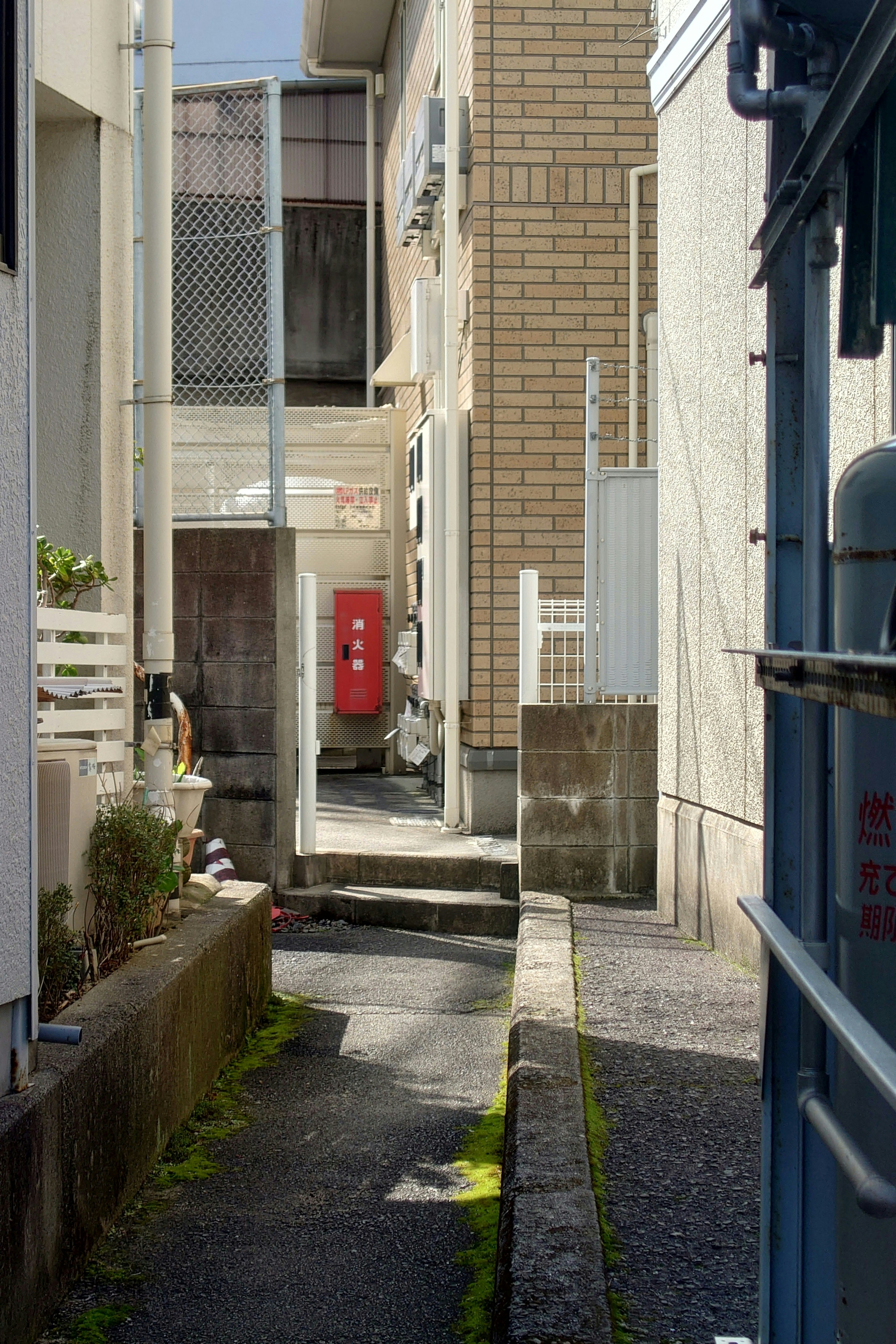 Allée étroite entre des maisons avec une boîte aux lettres rouge