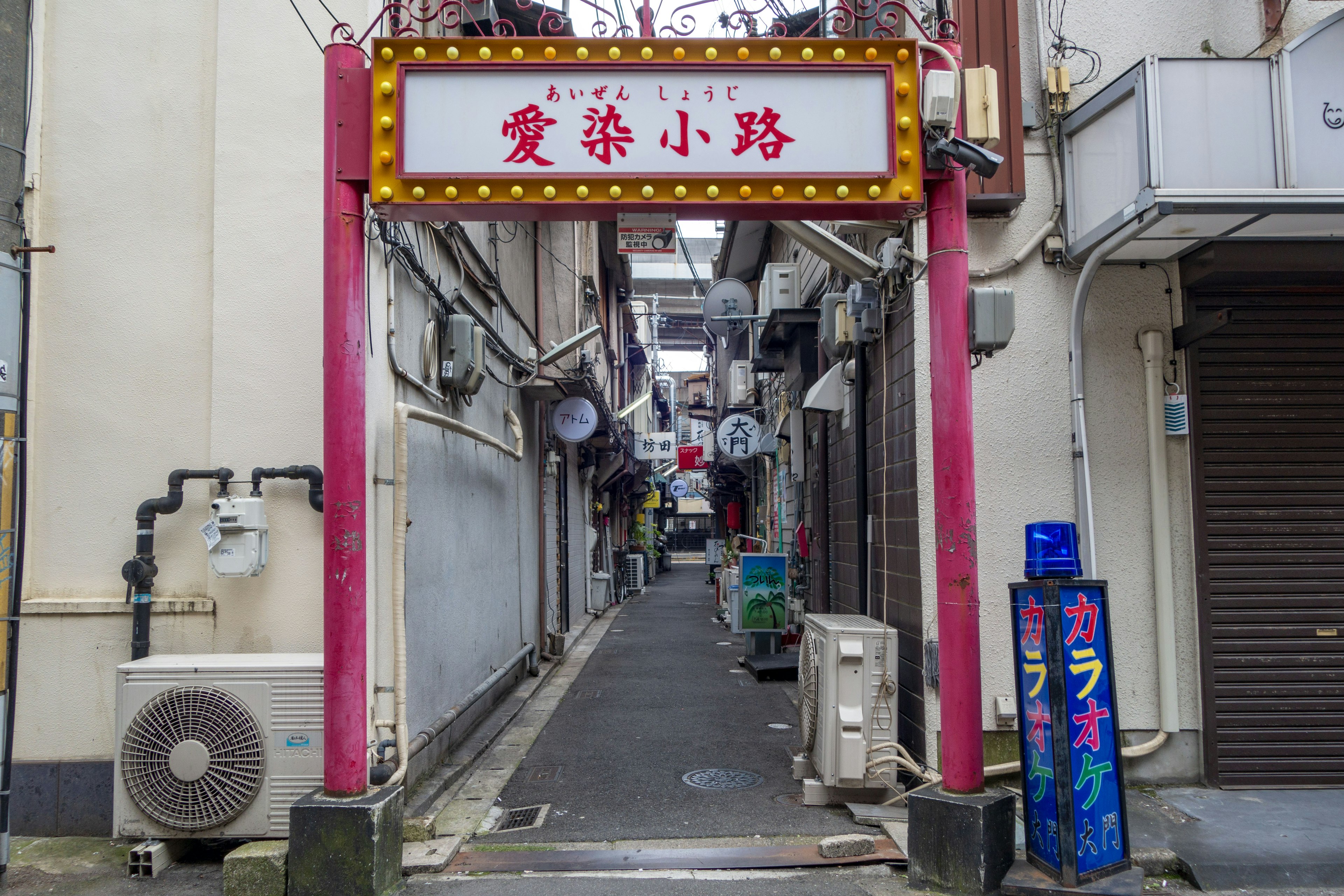 Eingang zu einer engen Gasse mit rotem Schild und weißen Buchstaben