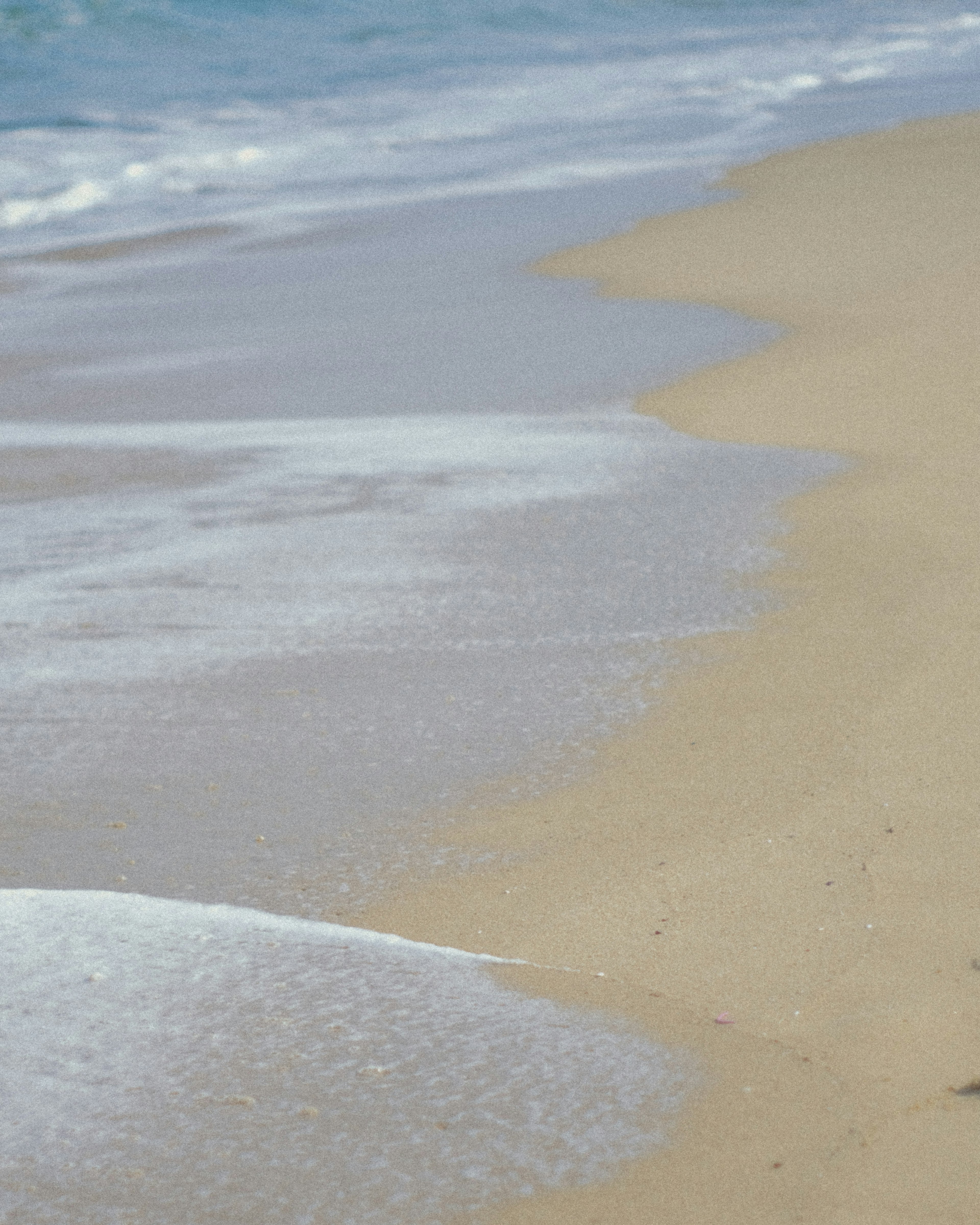 Wellen, die sanft an einen Sandstrand schlagen