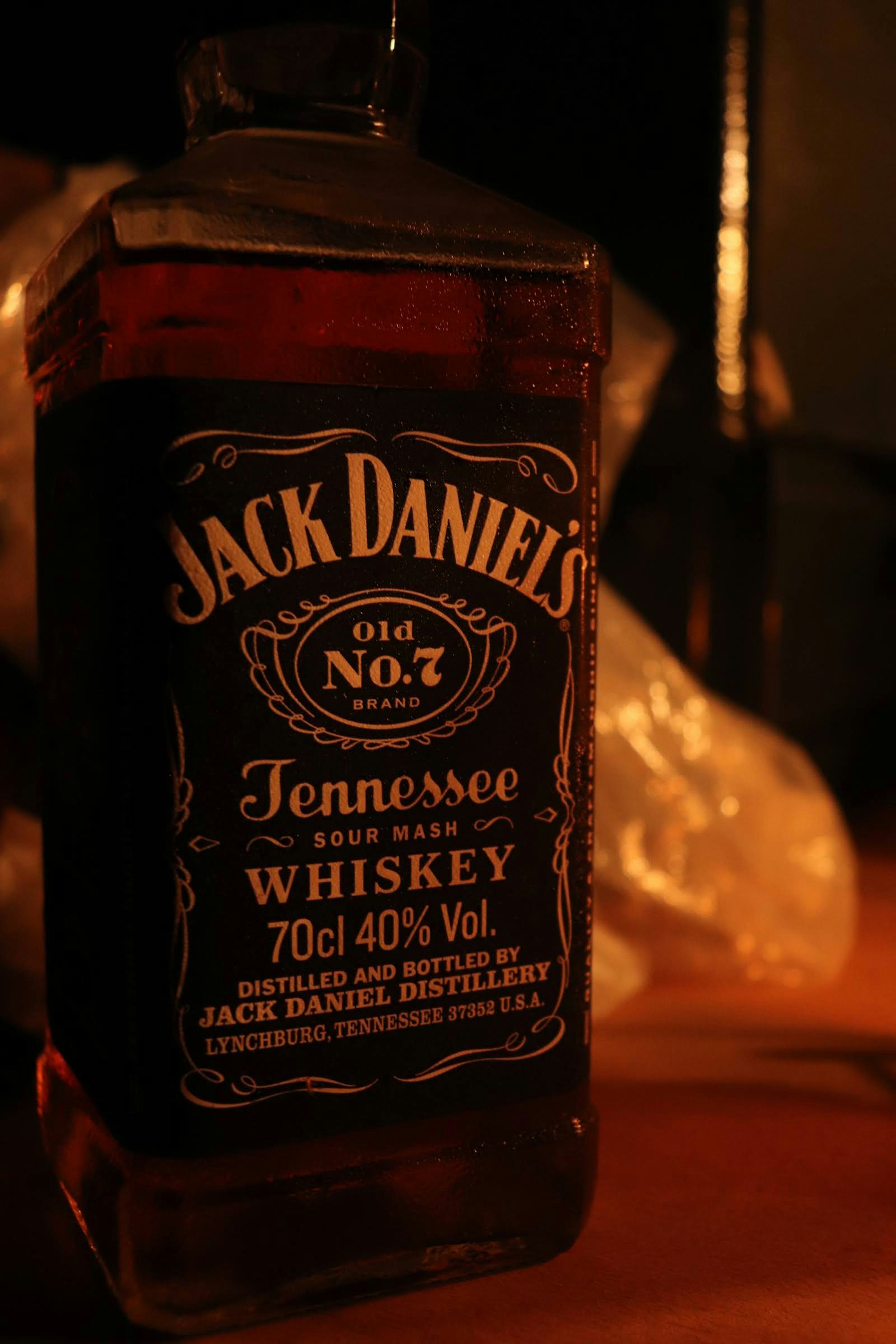 Jack Daniel's whiskey bottle reflecting light with a dark background