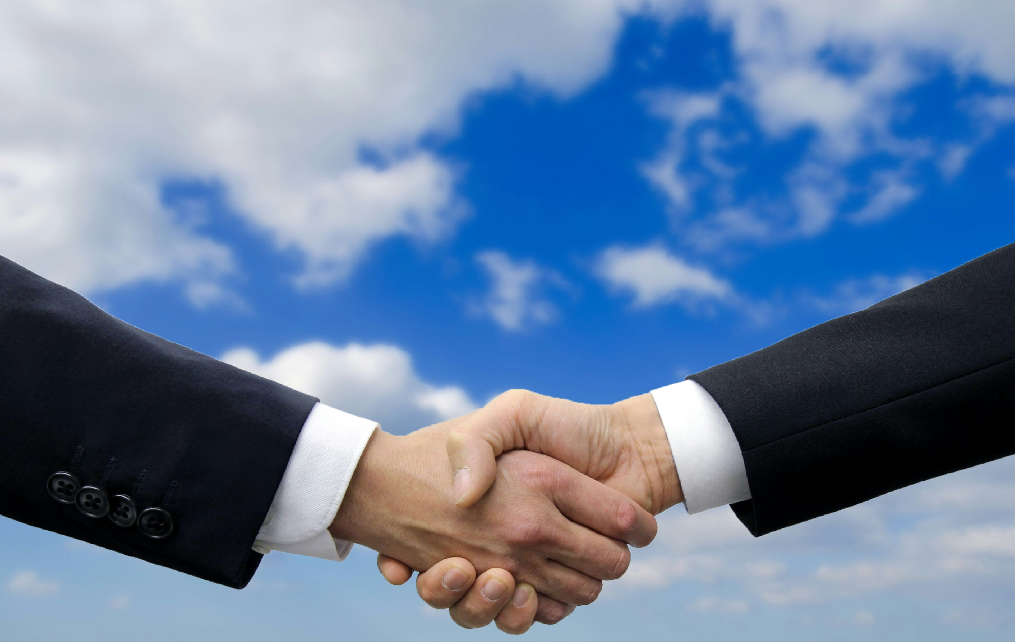 Businessmen shaking hands under a blue sky