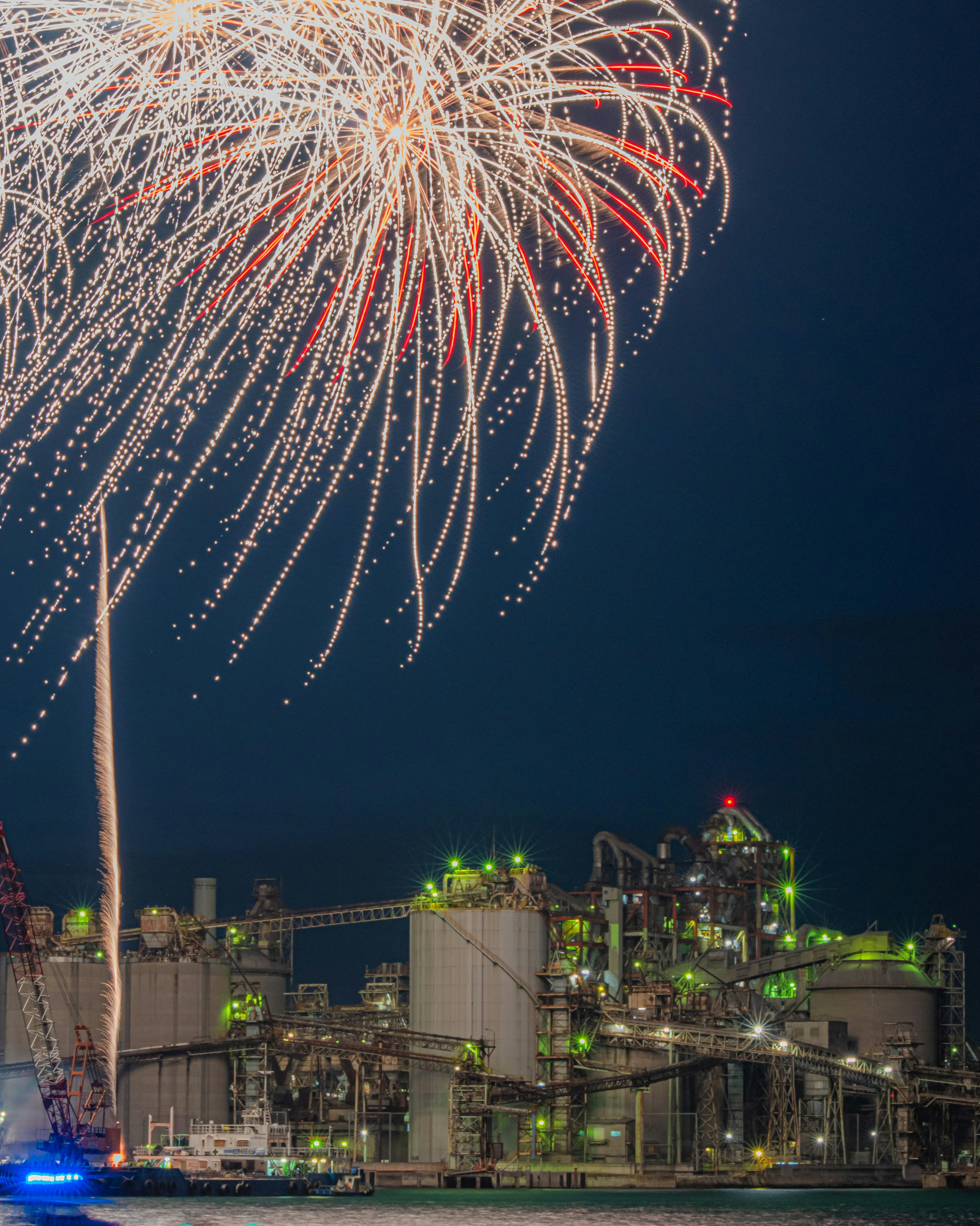 Fireworks display above an industrial facility at night