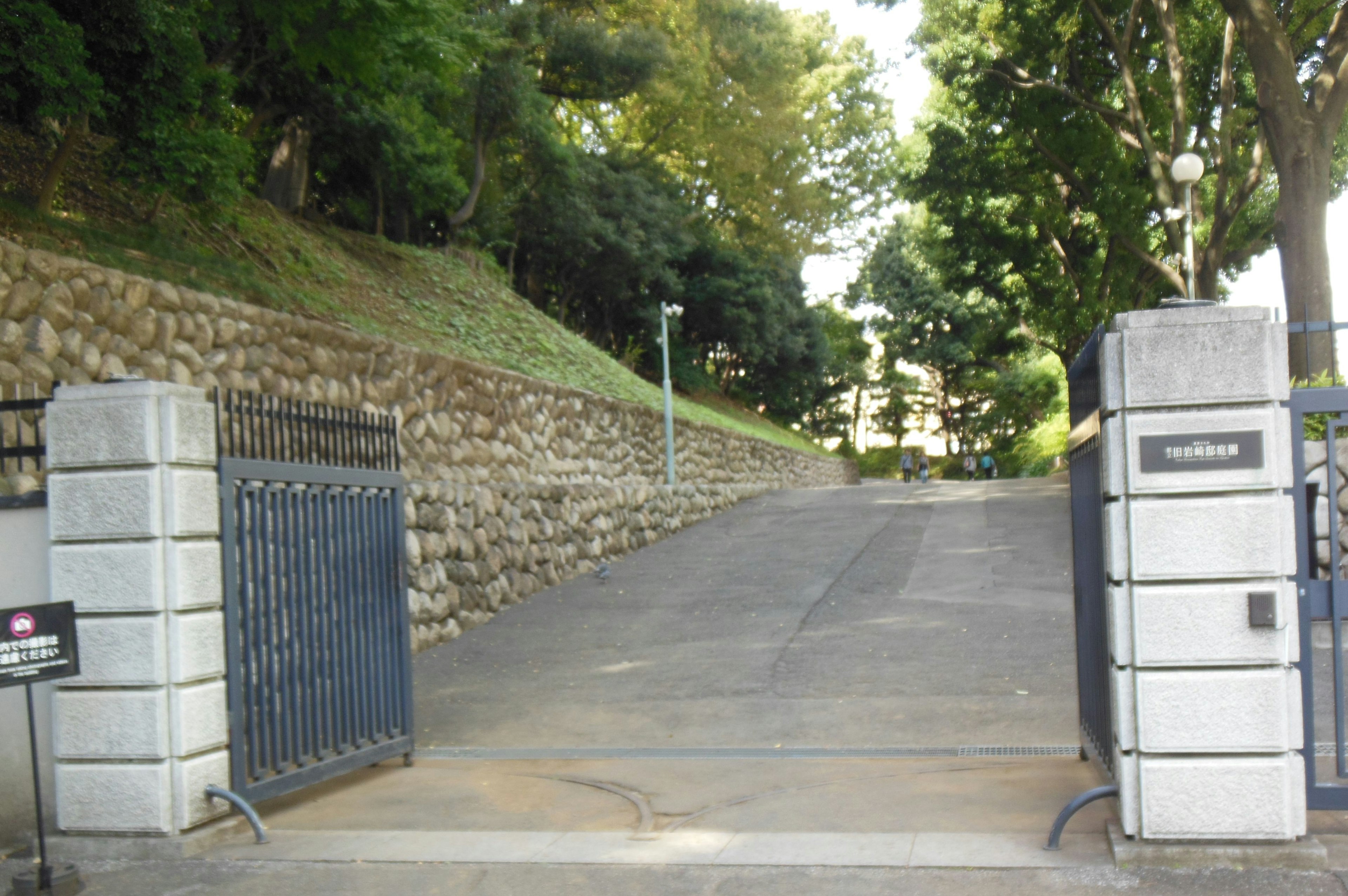 Paved pathway leading through a gate surrounded by lush greenery