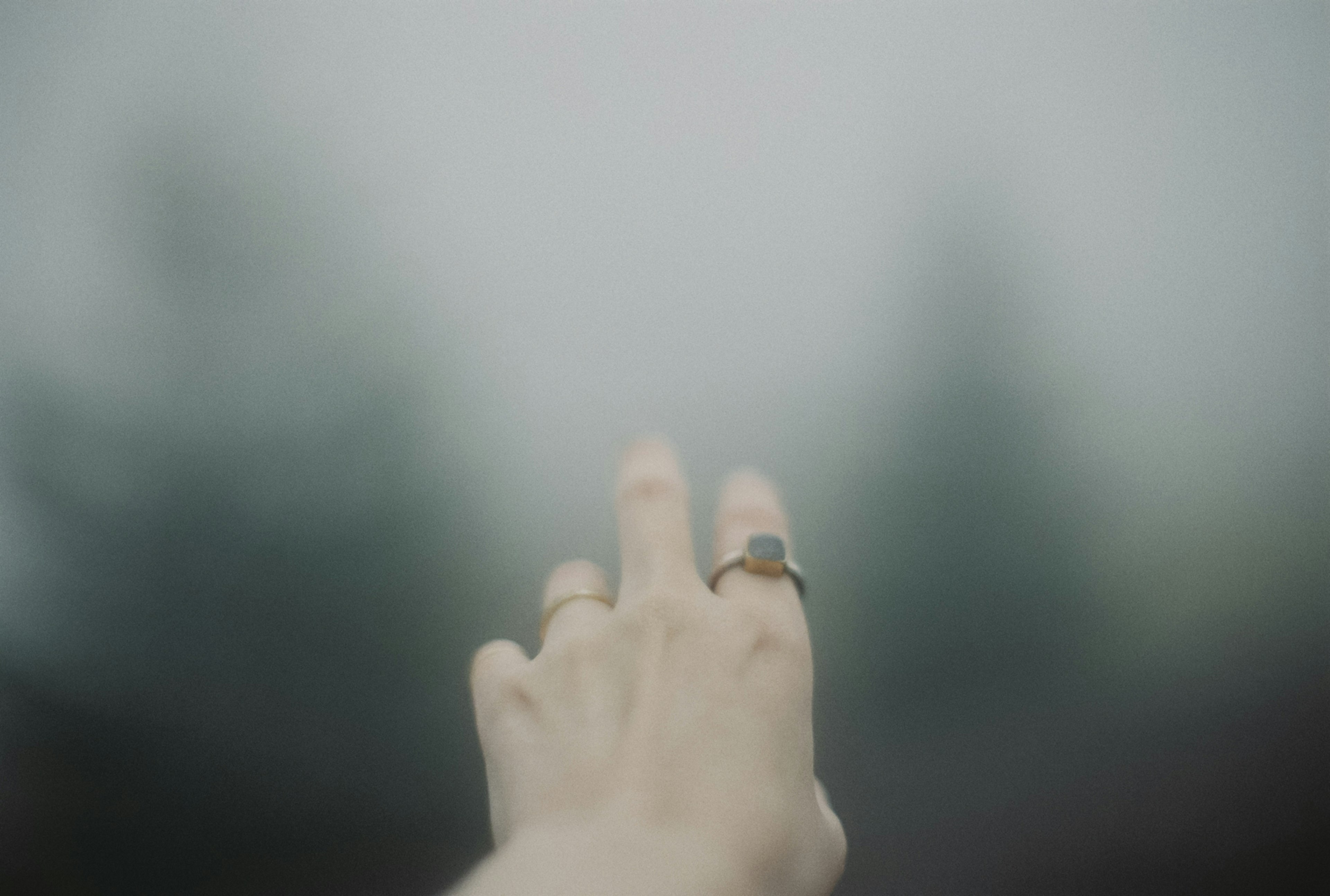 A hand reaching out with several rings against a blurred background