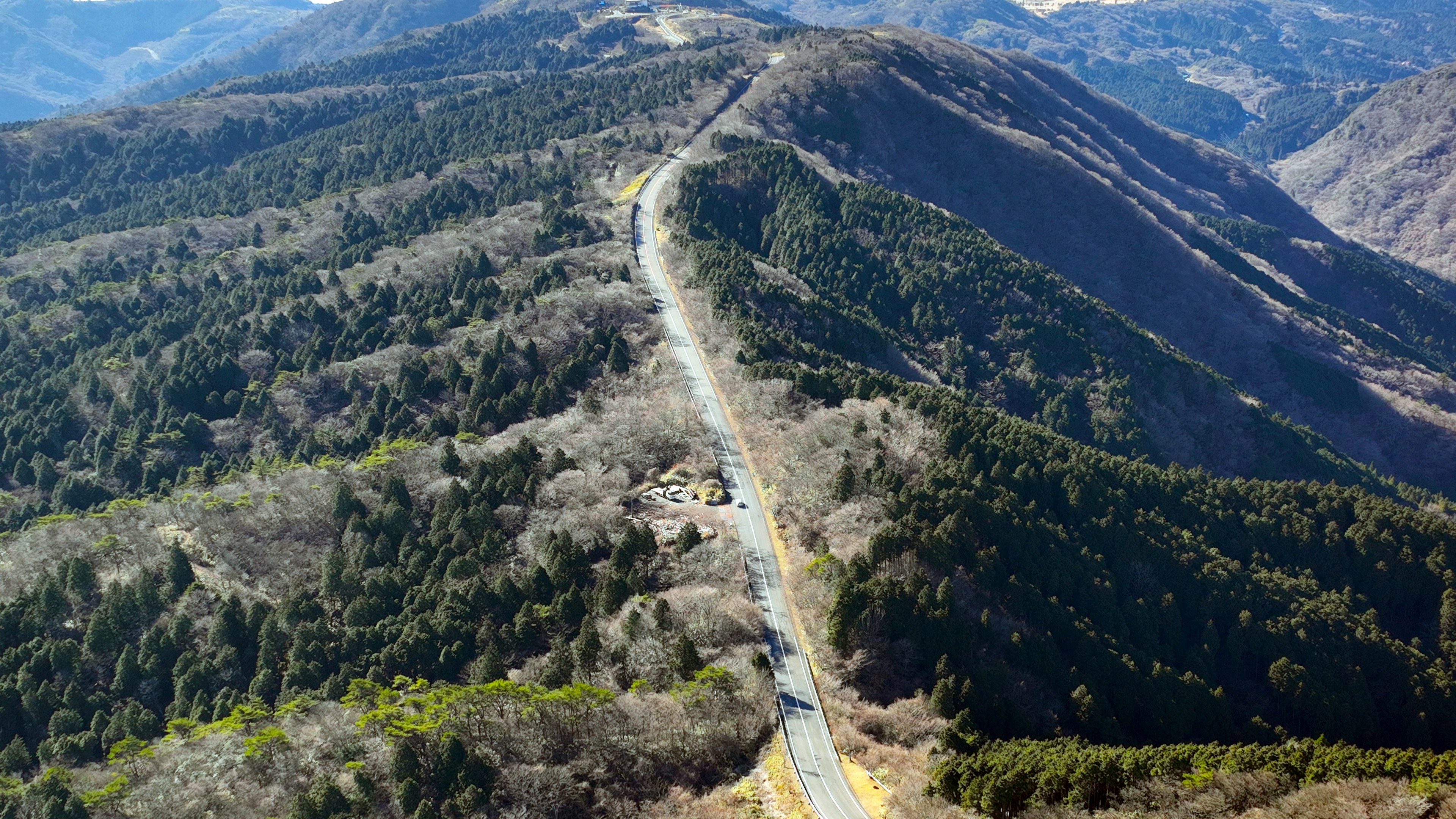 Aerial view of a winding road through a mountainous landscape with forests