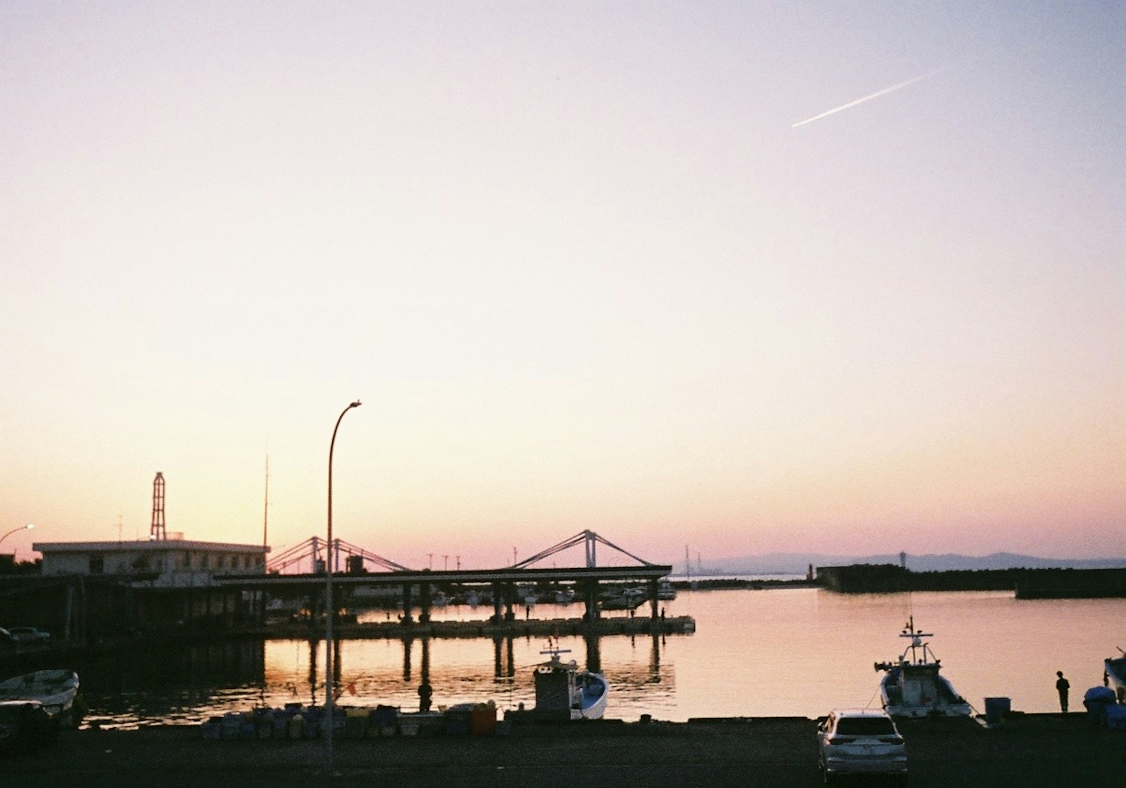 Ruhige Hafen-Sonnenuntergangsszene mit vertäuten Booten und ruhigem Wasser