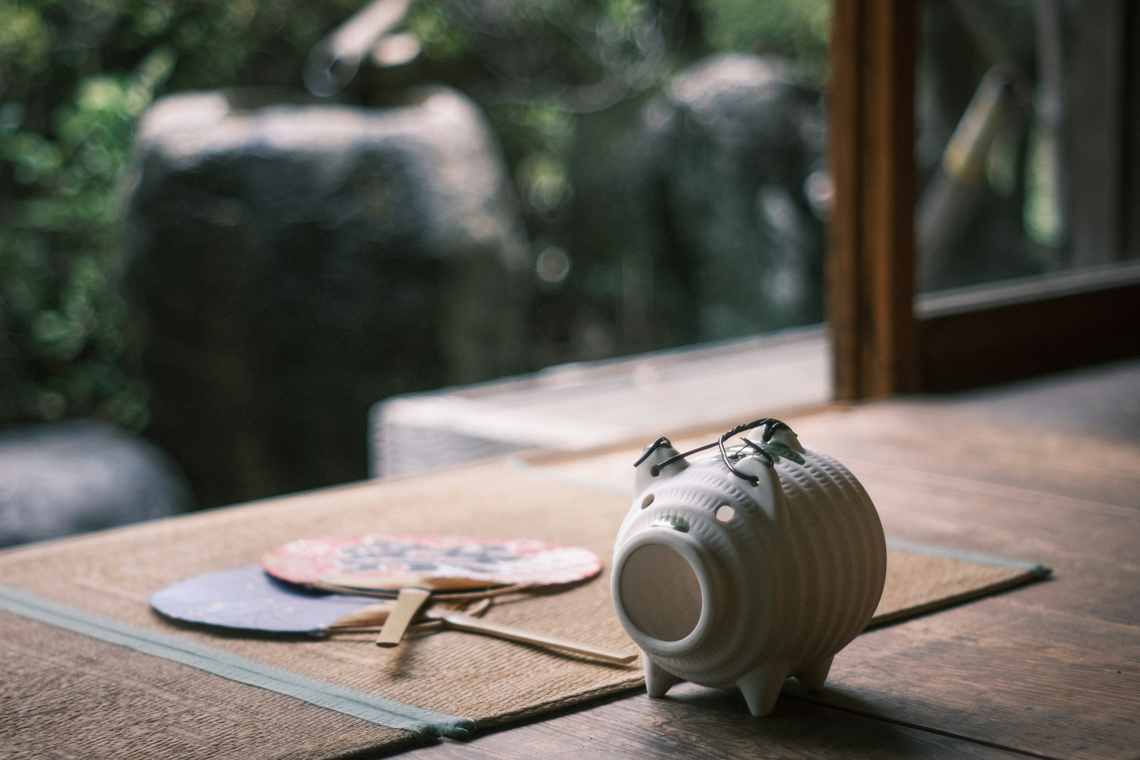 A white piggy bank alongside traditional Japanese items in a tranquil indoor setting