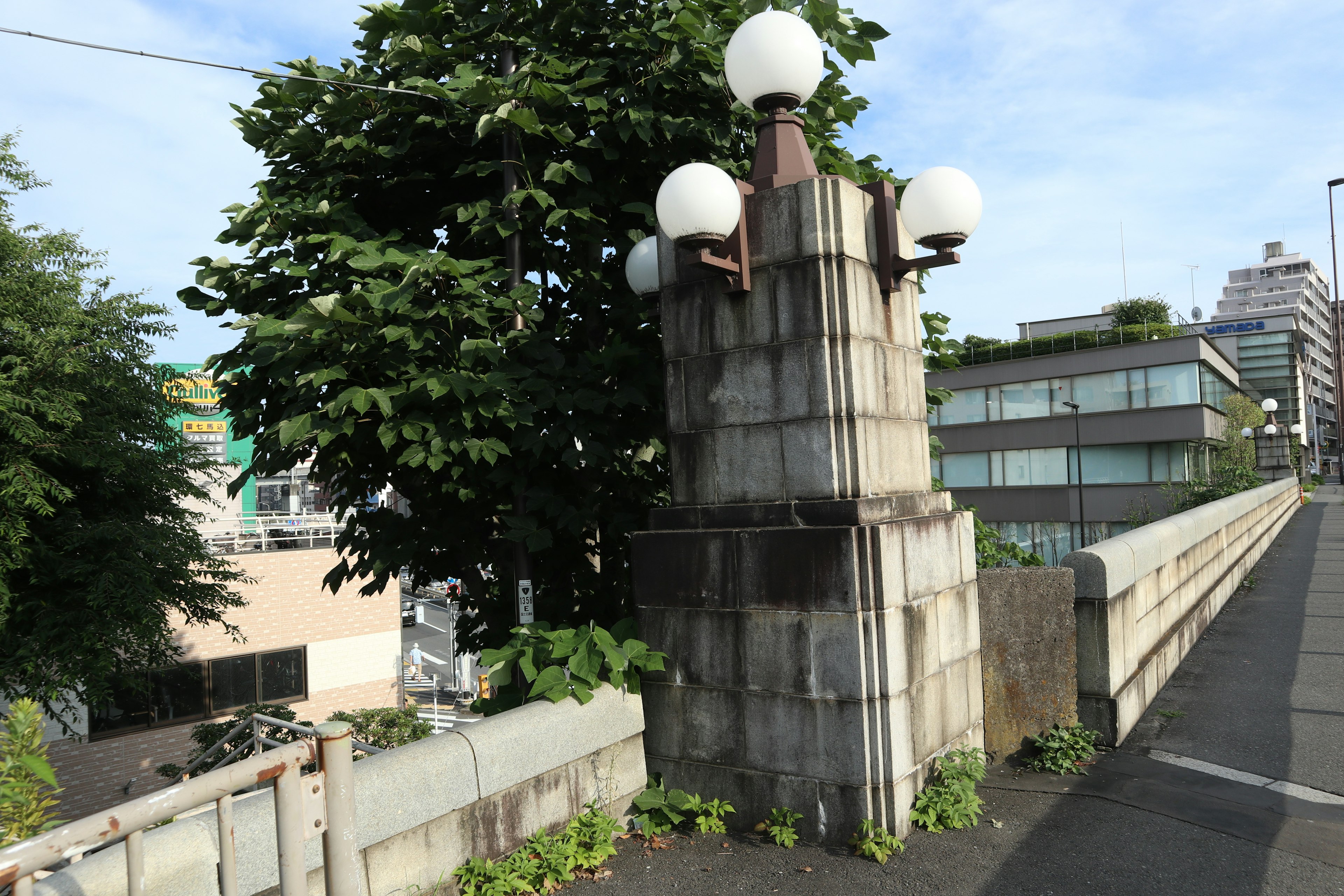 Concrete bridge pillar with street lamps and greenery