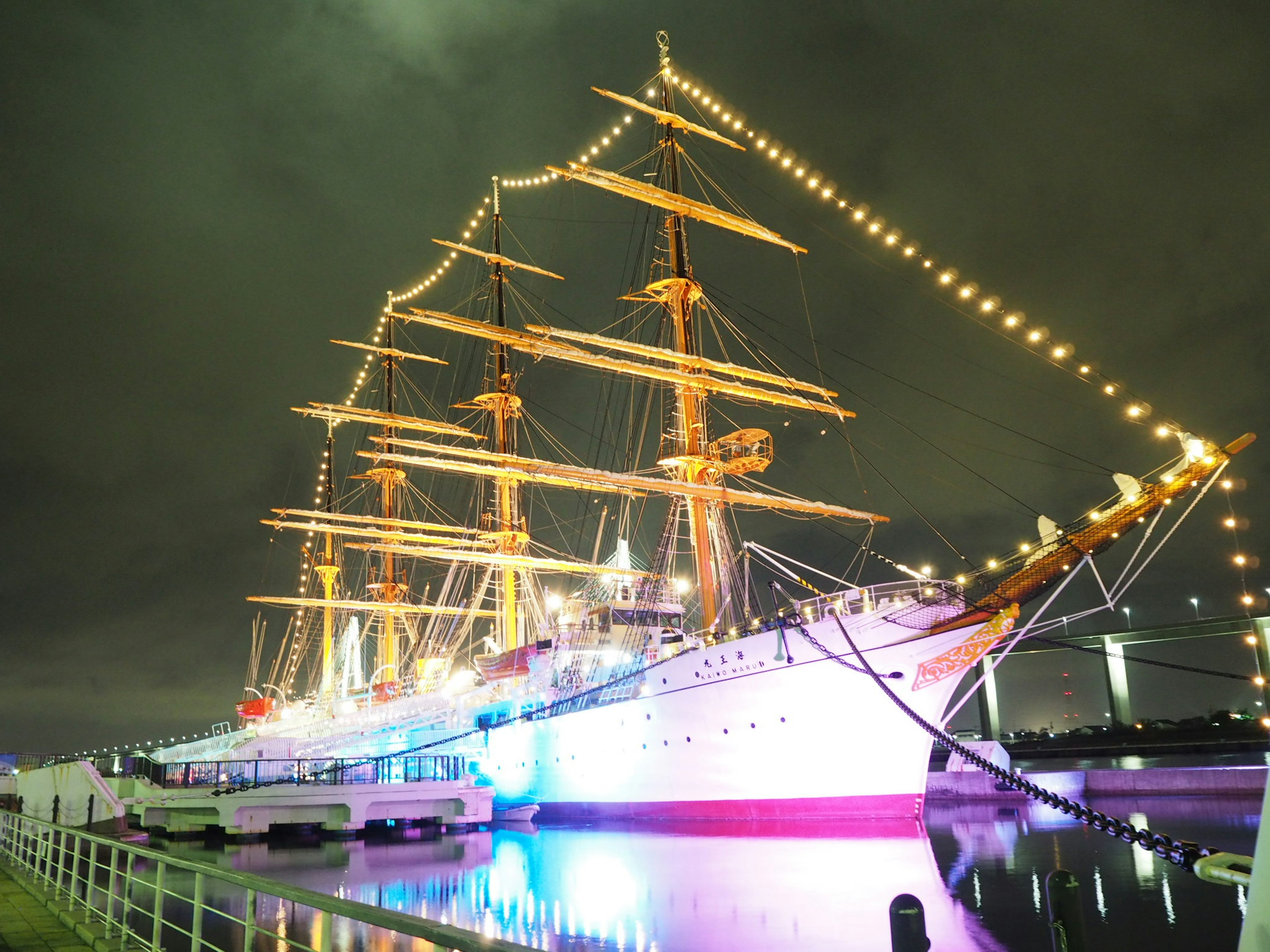 A beautiful tall ship illuminated at night with colorful lights