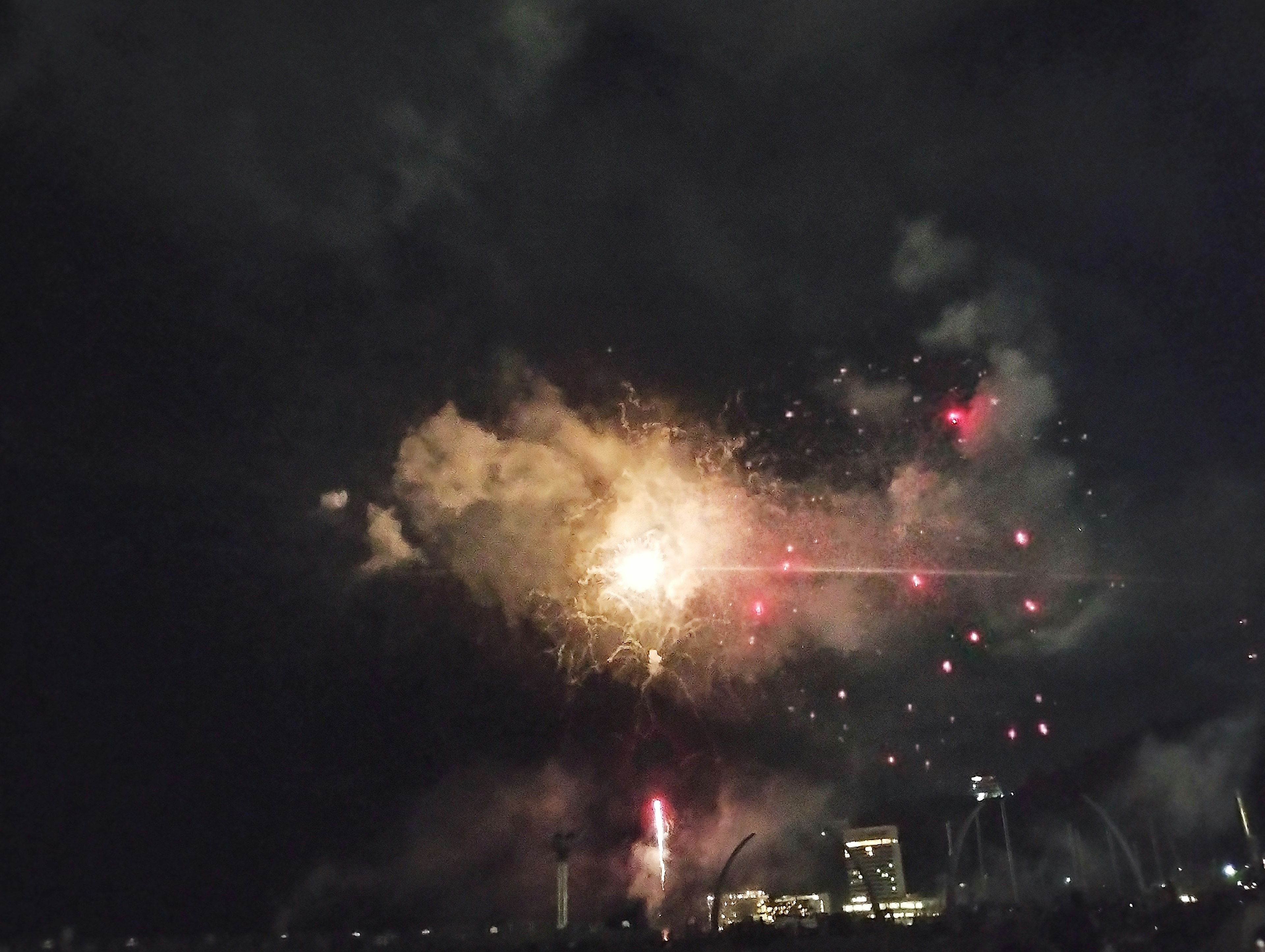 Fuegos artificiales estallando en un oscuro cielo nocturno con humo