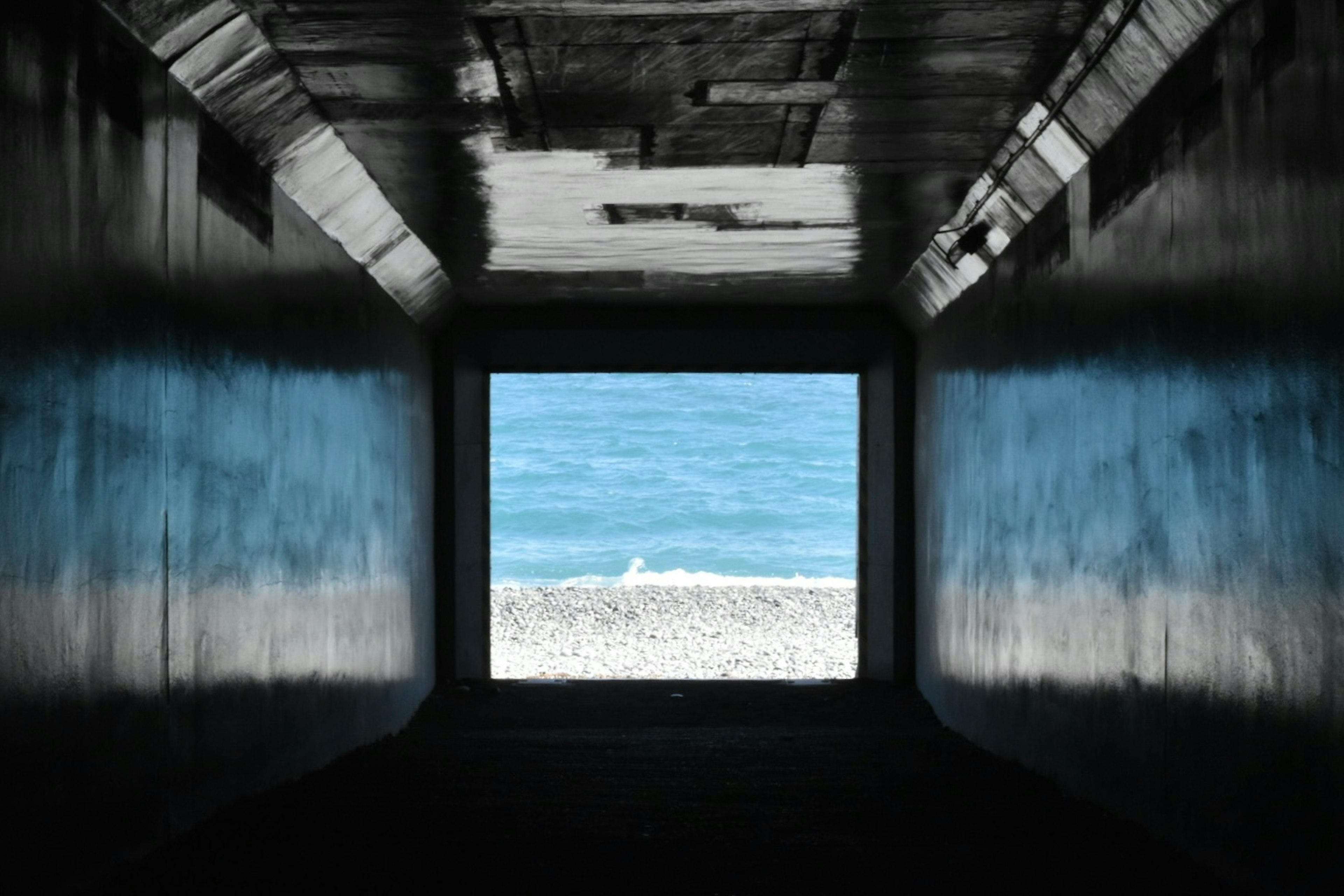 Vue de la mer bleue et de la plage de sable à travers un tunnel