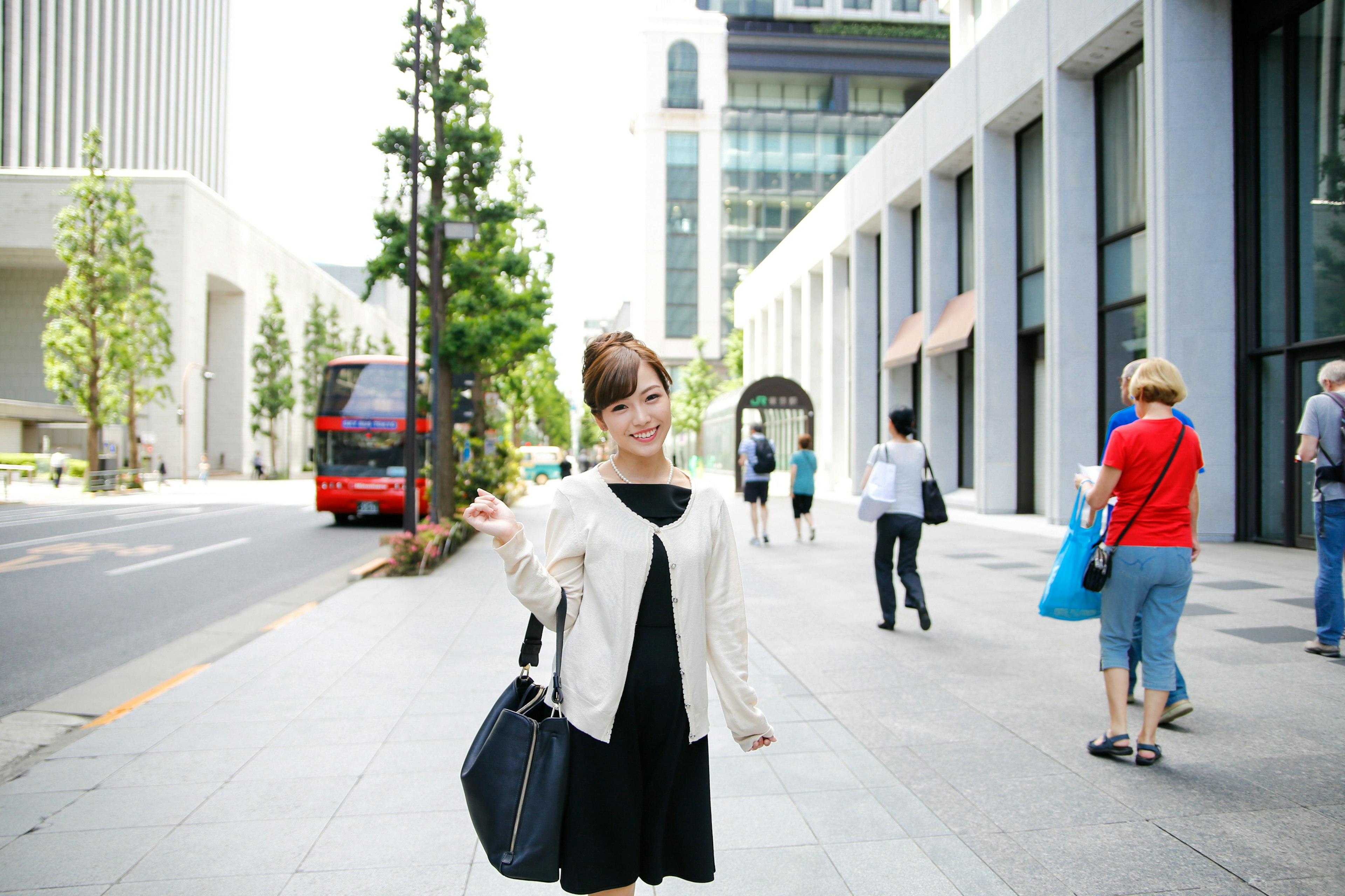 A woman posing on the street with skyscrapers and a bus in the background