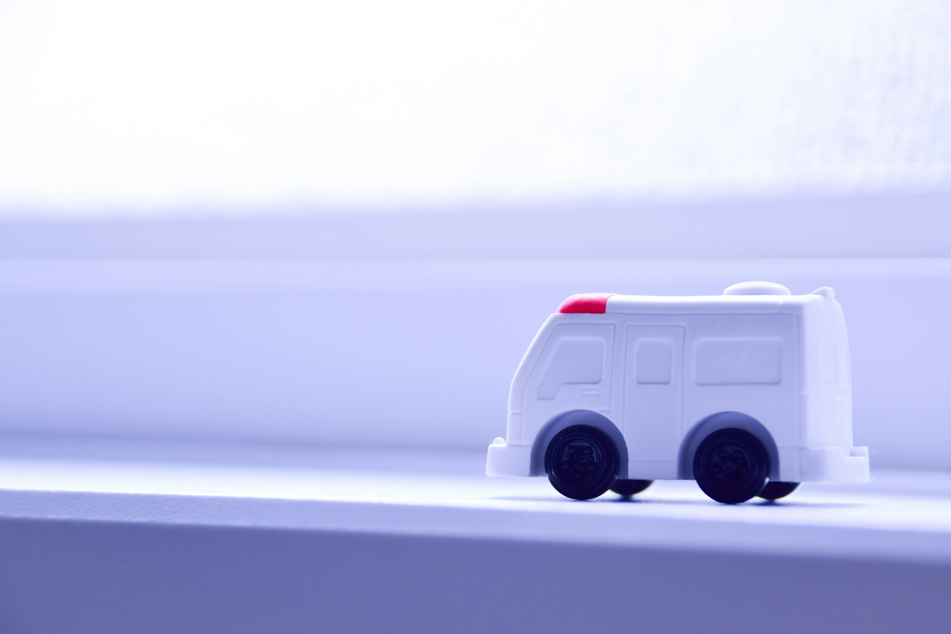 A small white toy ambulance placed on a bright windowsill