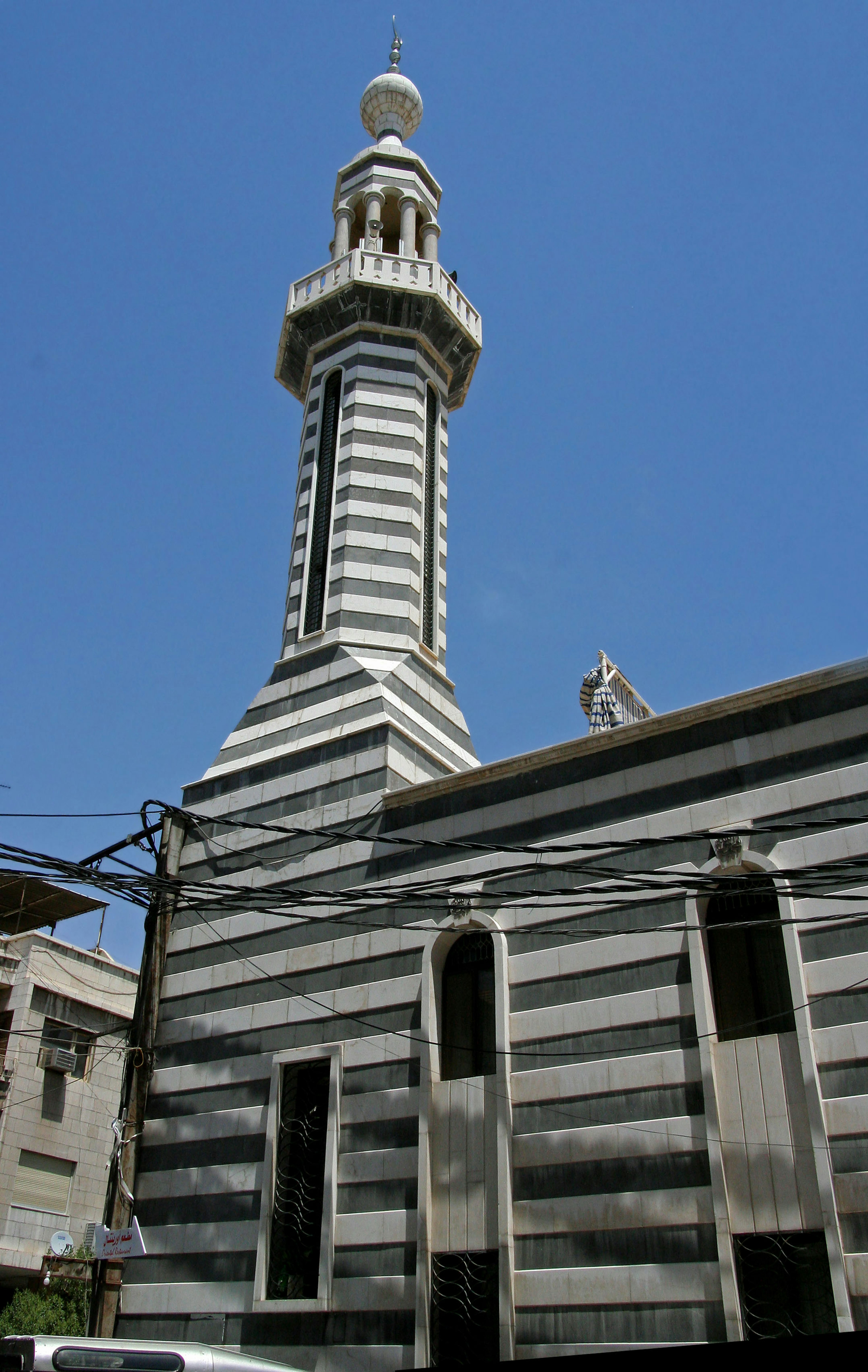 Striped mosque minaret standing under a blue sky