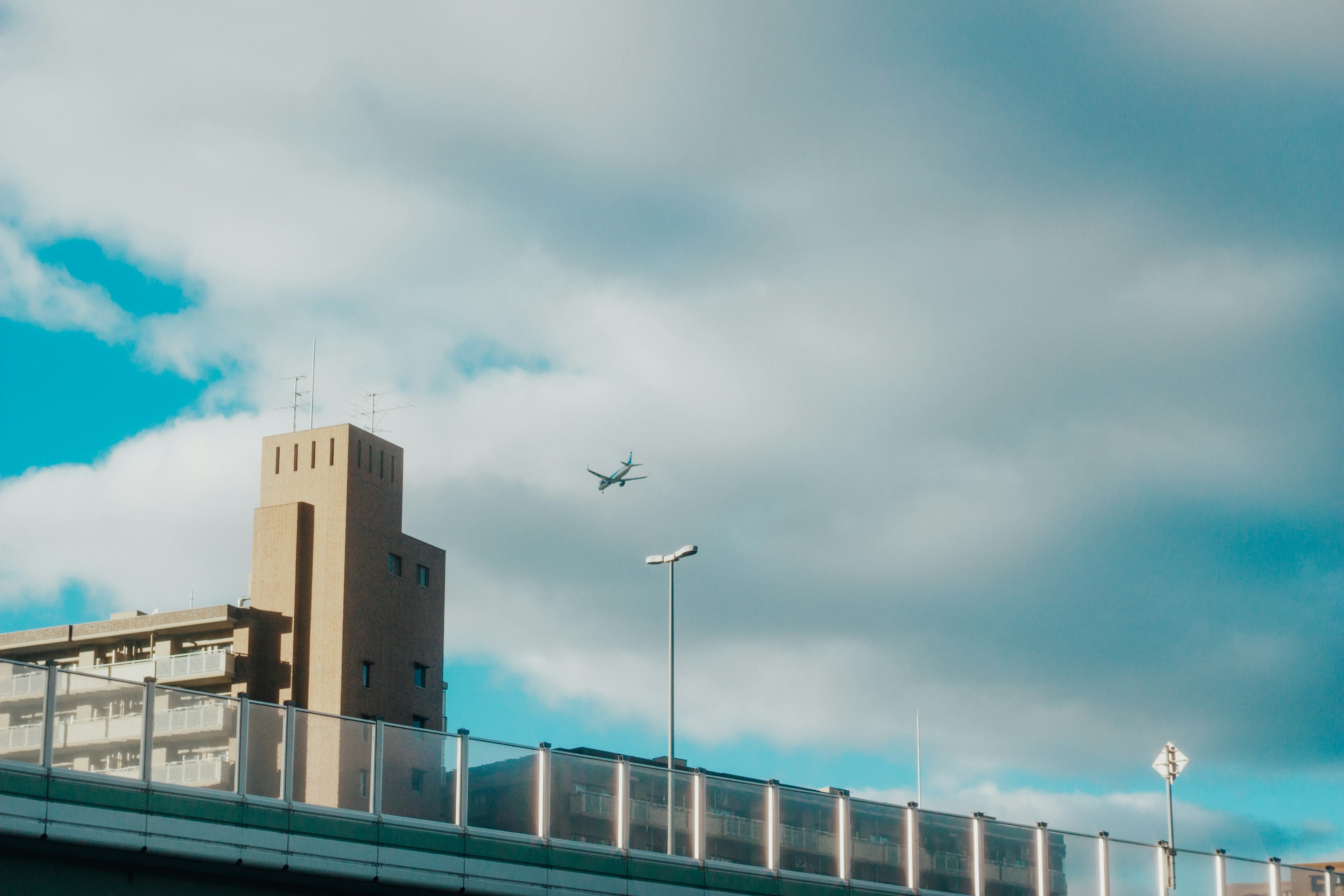 Un avión volando bajo un cielo azul con edificios urbanos y un puente a la vista