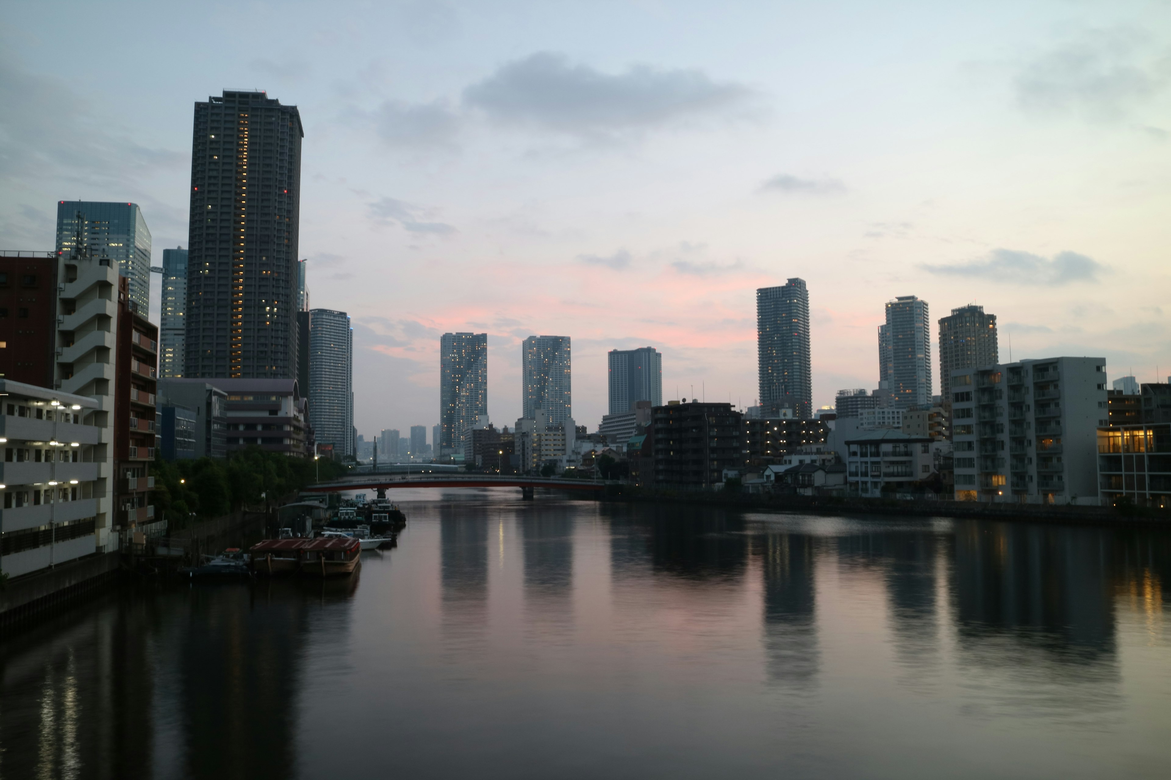 Horizonte de la ciudad al atardecer con rascacielos y reflejos en el agua tranquila