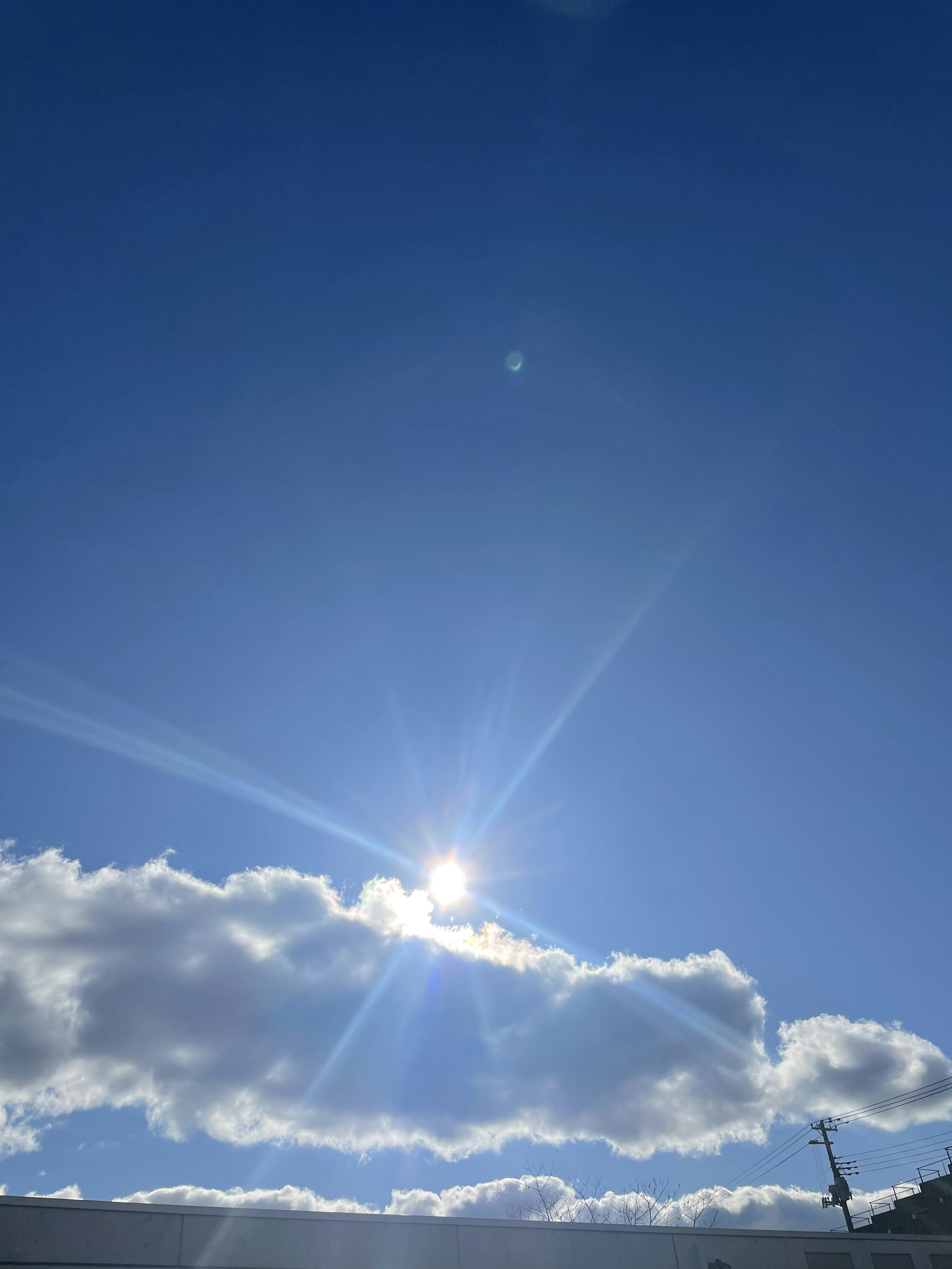 Bright sun shining in a clear blue sky with white clouds