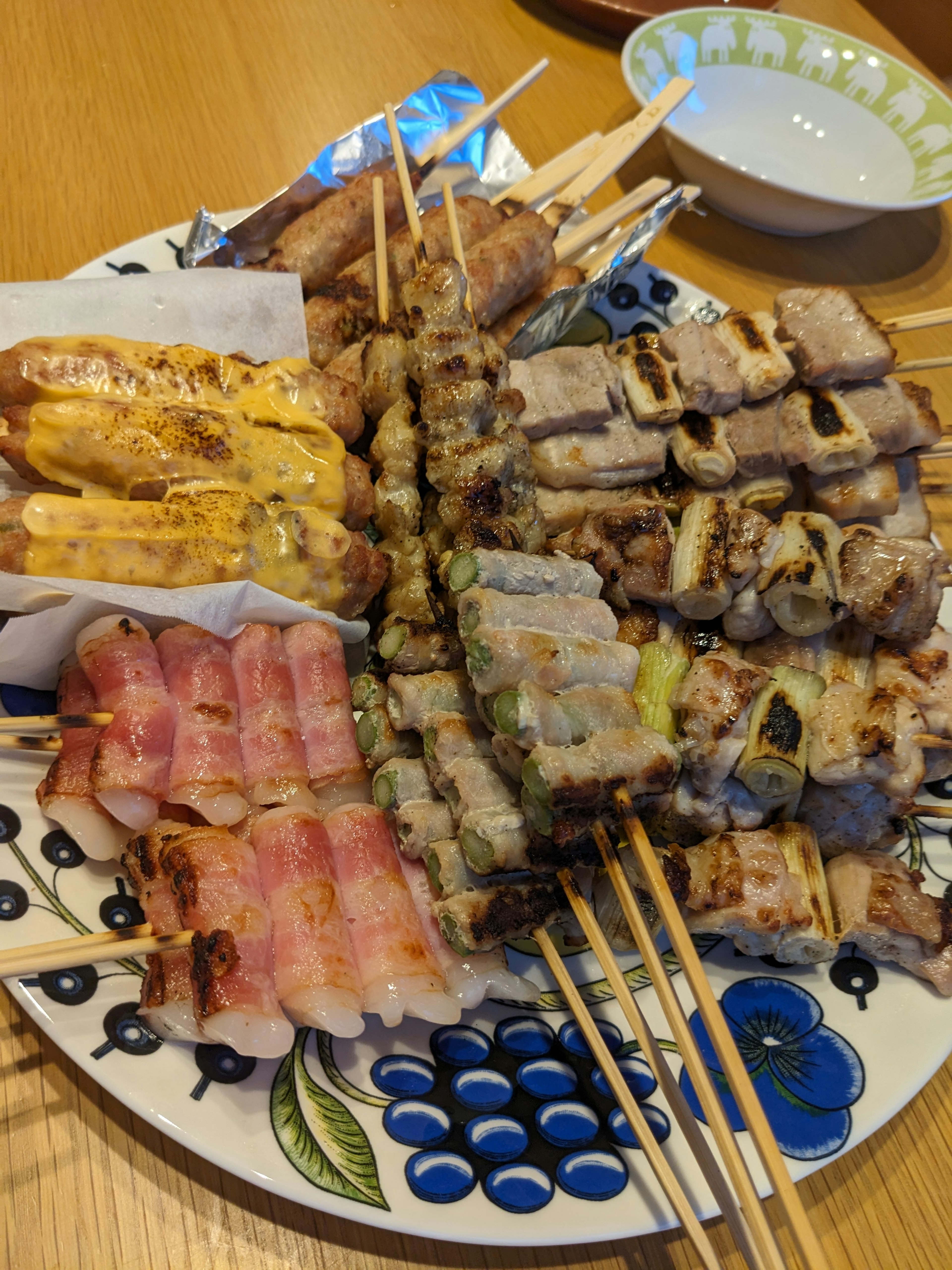 A platter of assorted grilled skewers featuring various meats and vegetables on a decorative plate