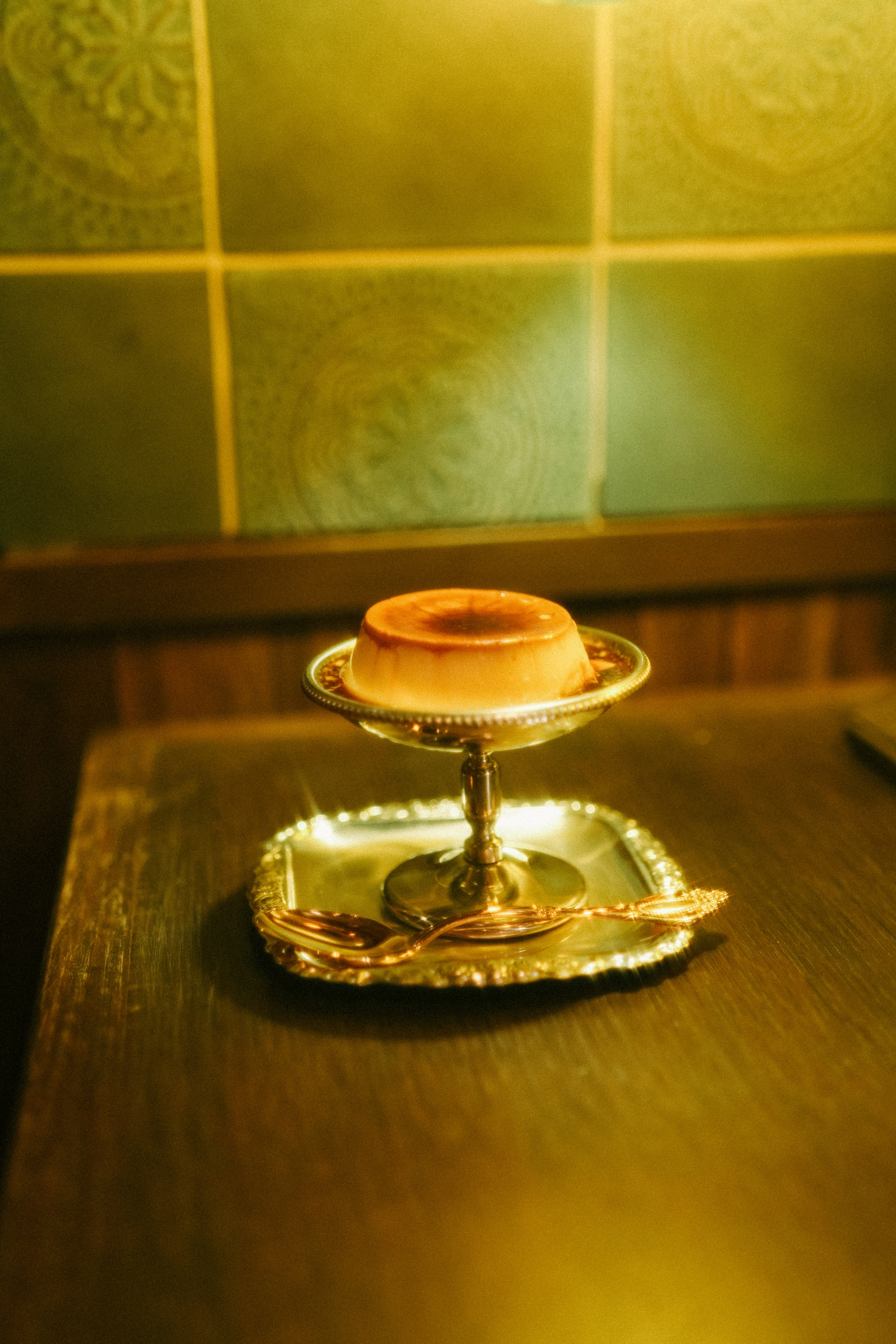 A dessert resembling a cupcake sits on a silver tray on a wooden table