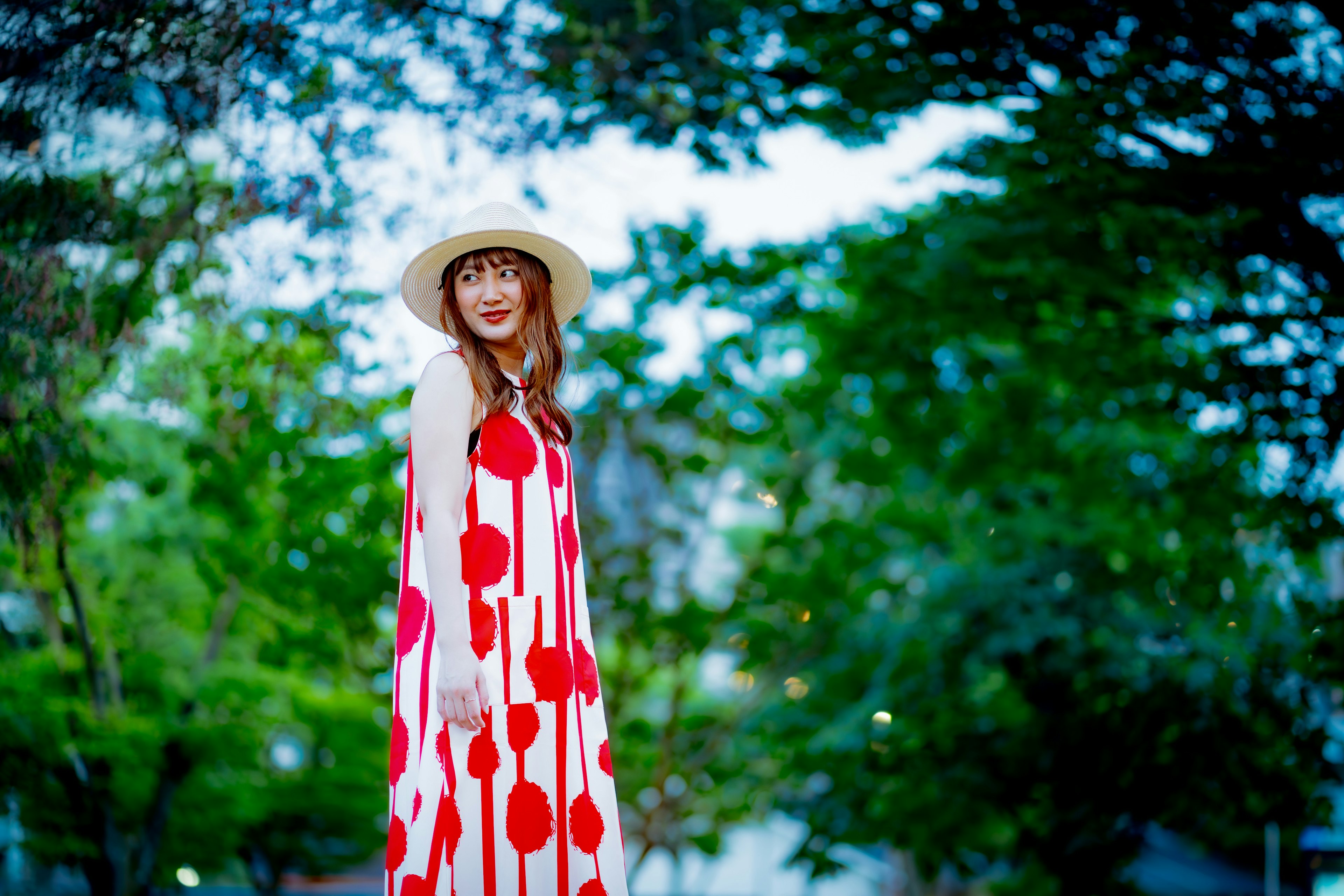 Woman in a red polka dot dress smiling against a green background