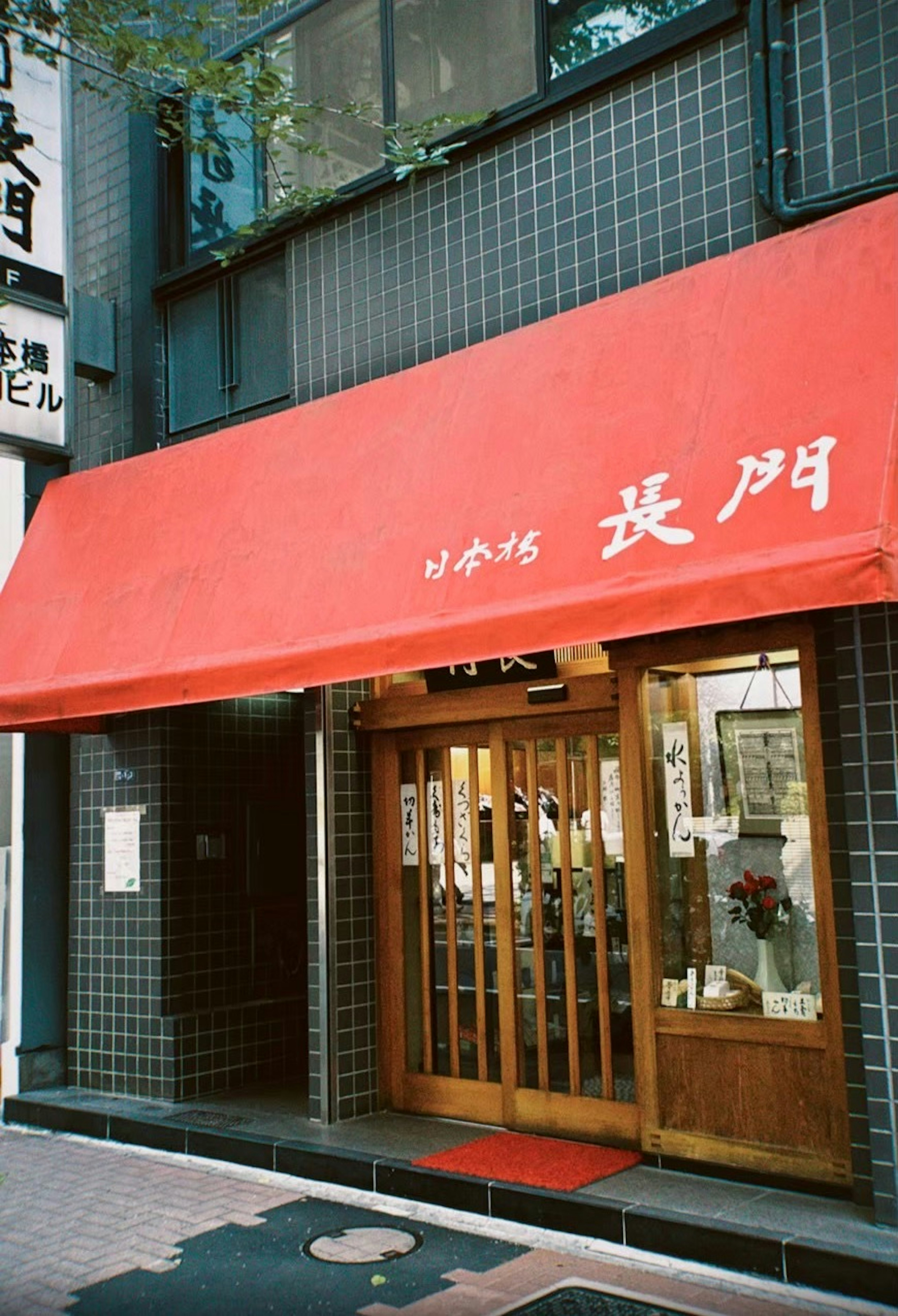 Extérieur de restaurant avec auvent rouge et porte en bois