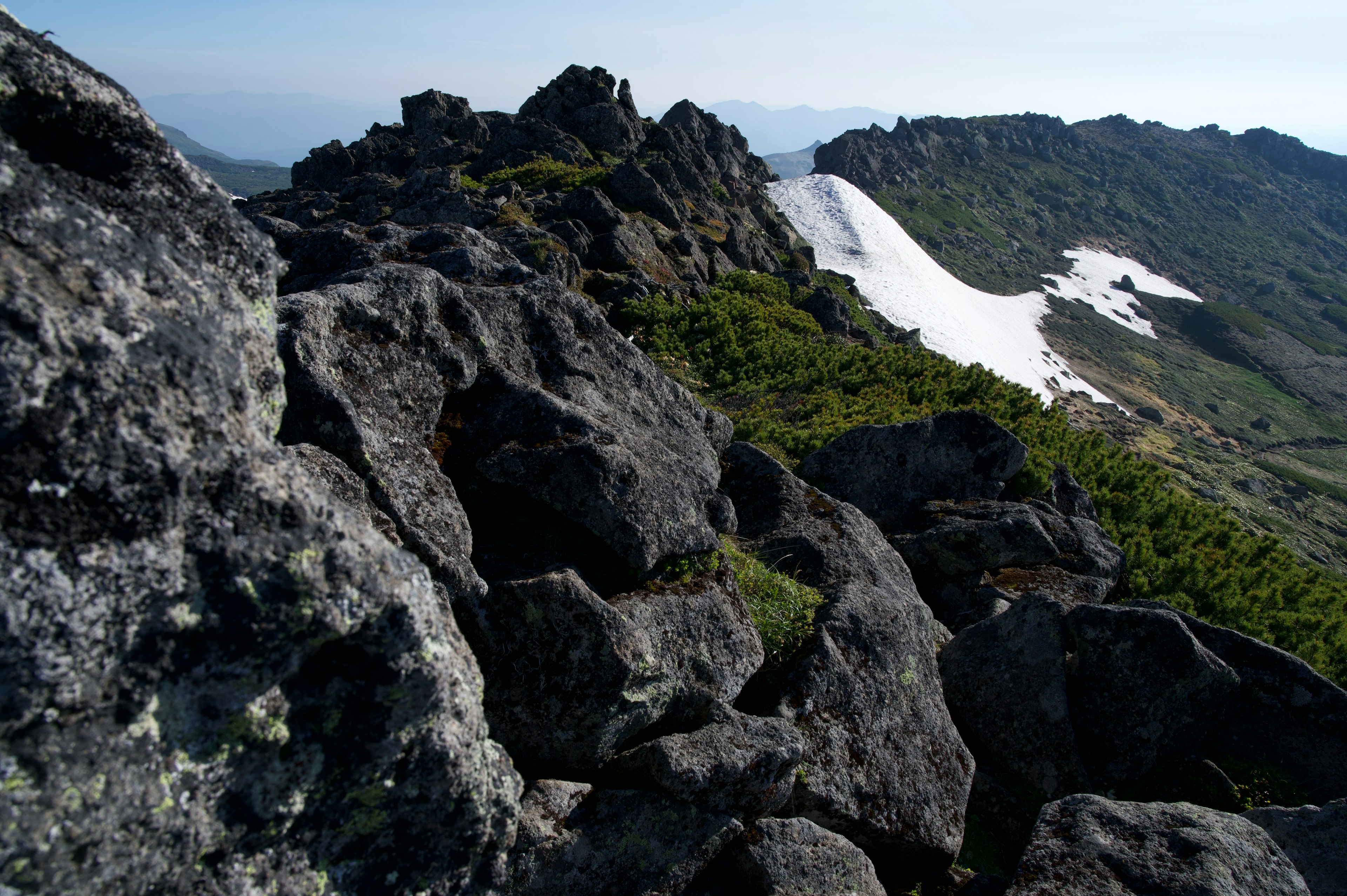 Paisaje montañoso con terreno rocoso y nieve restante