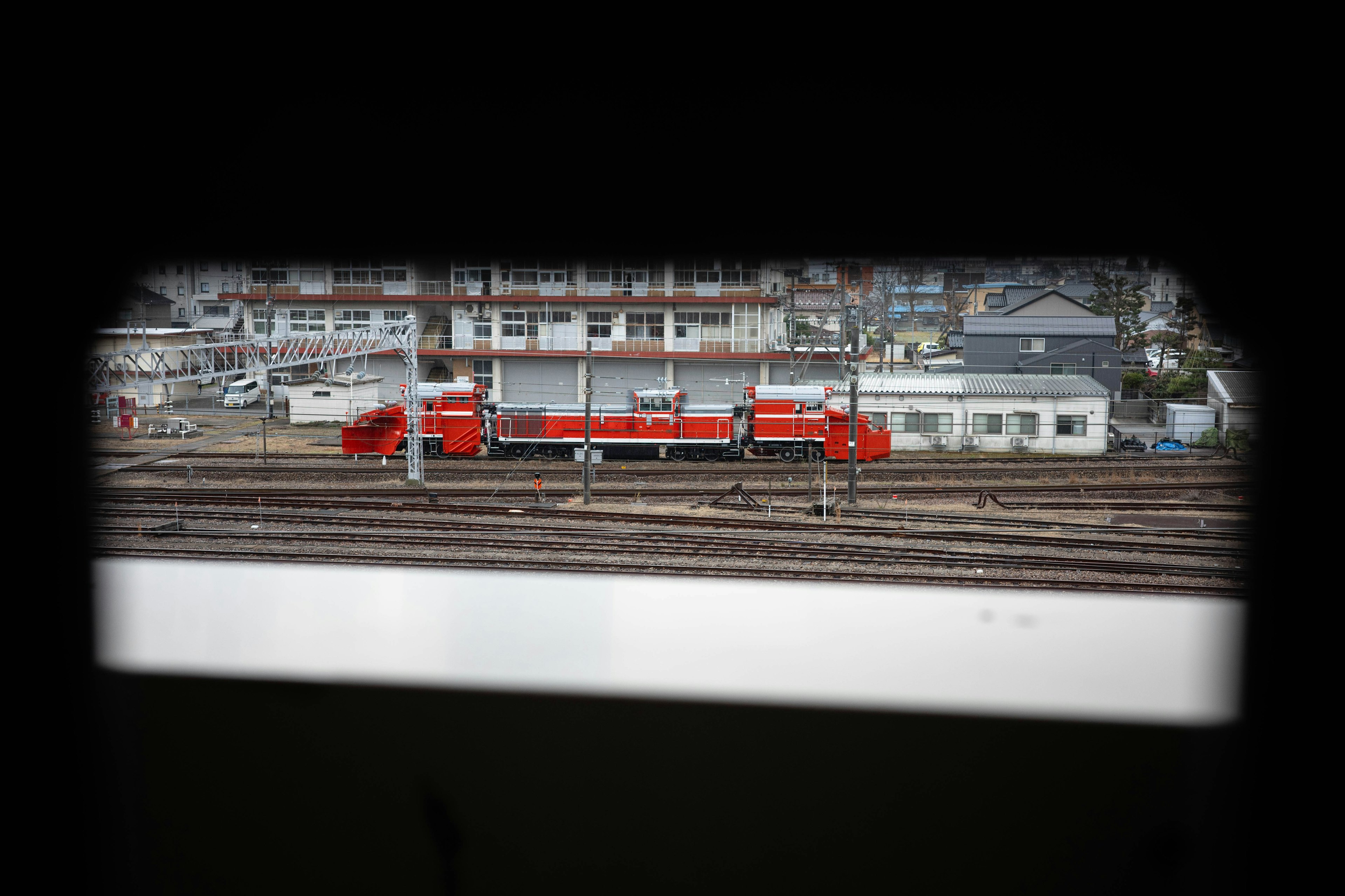 Red locomotive parked on the tracks with buildings in the background