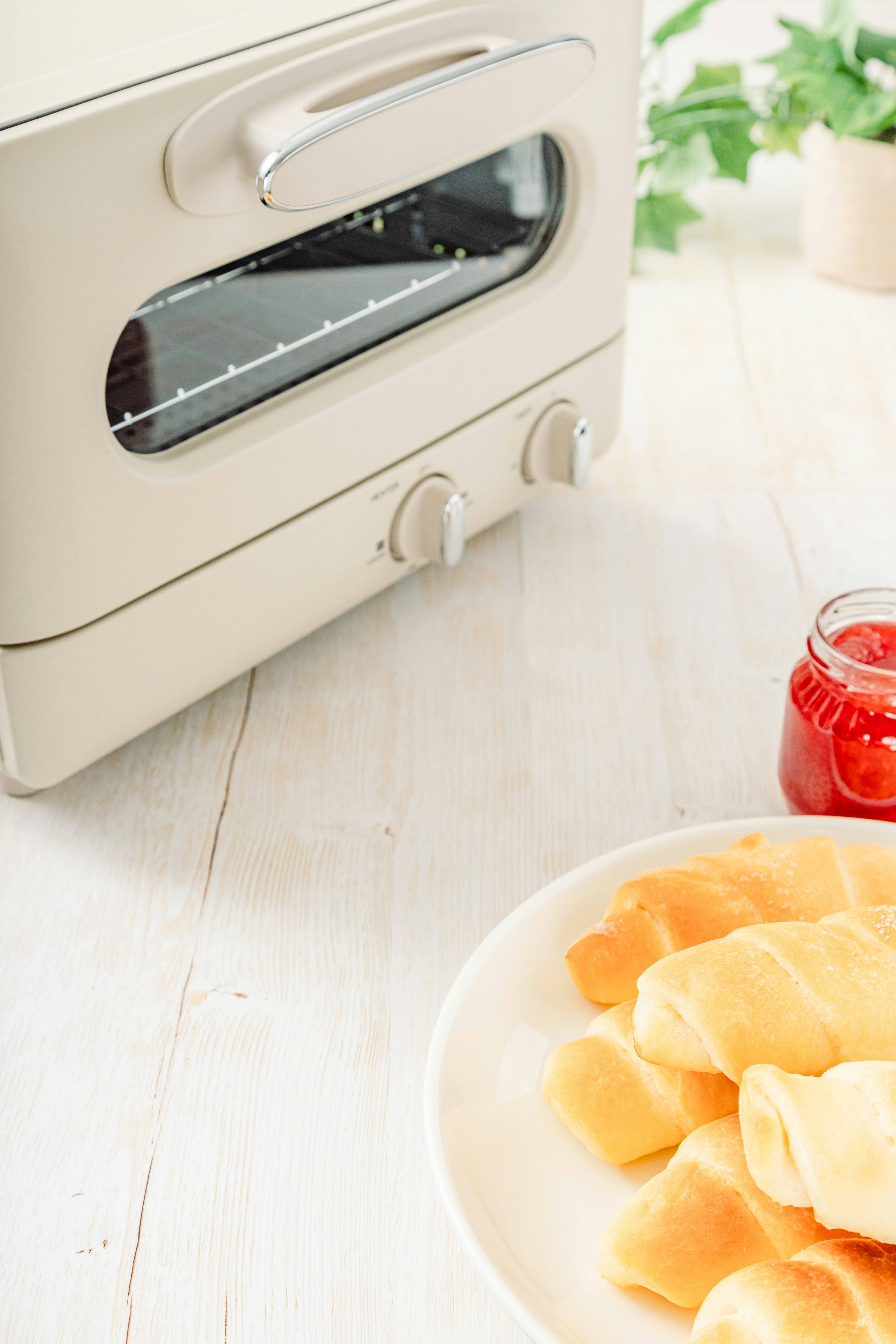 Un four à toaster sur le comptoir à côté d'une assiette de fruits tranchés et d'un pot de confiture