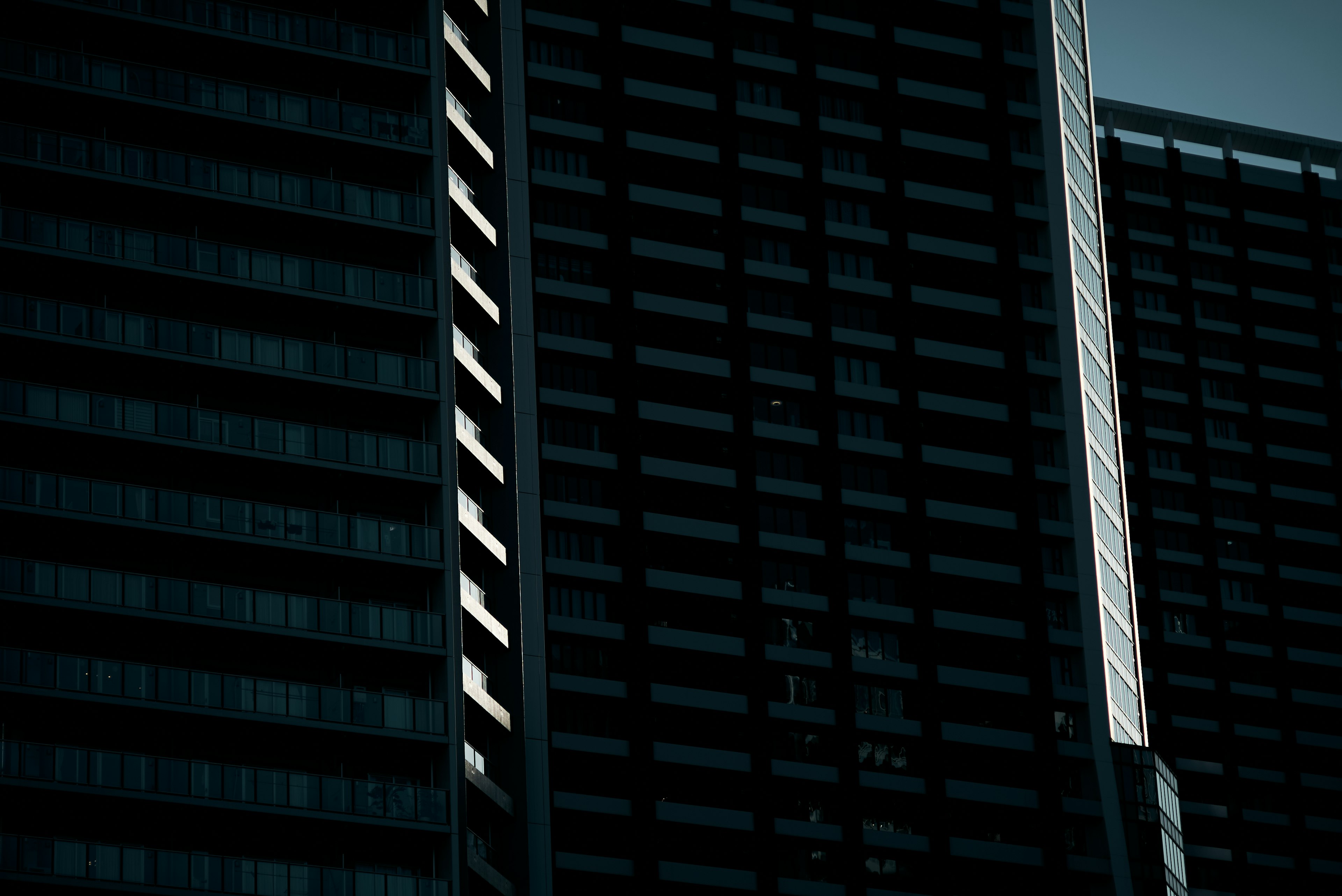 Façade d'un immeuble de grande hauteur sombre avec des reflets de lumière