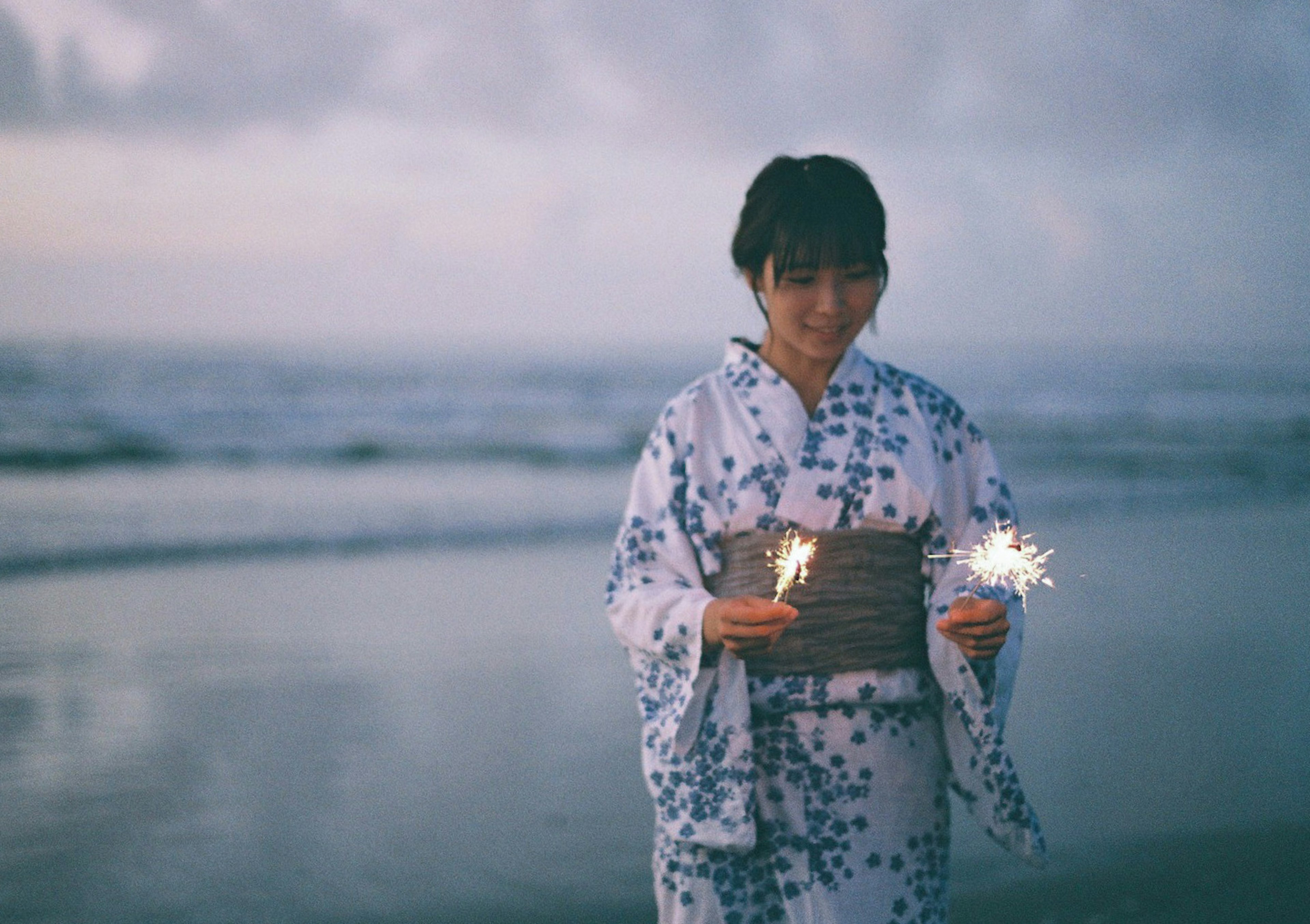 海辺で花火を持つ着物を着た女性