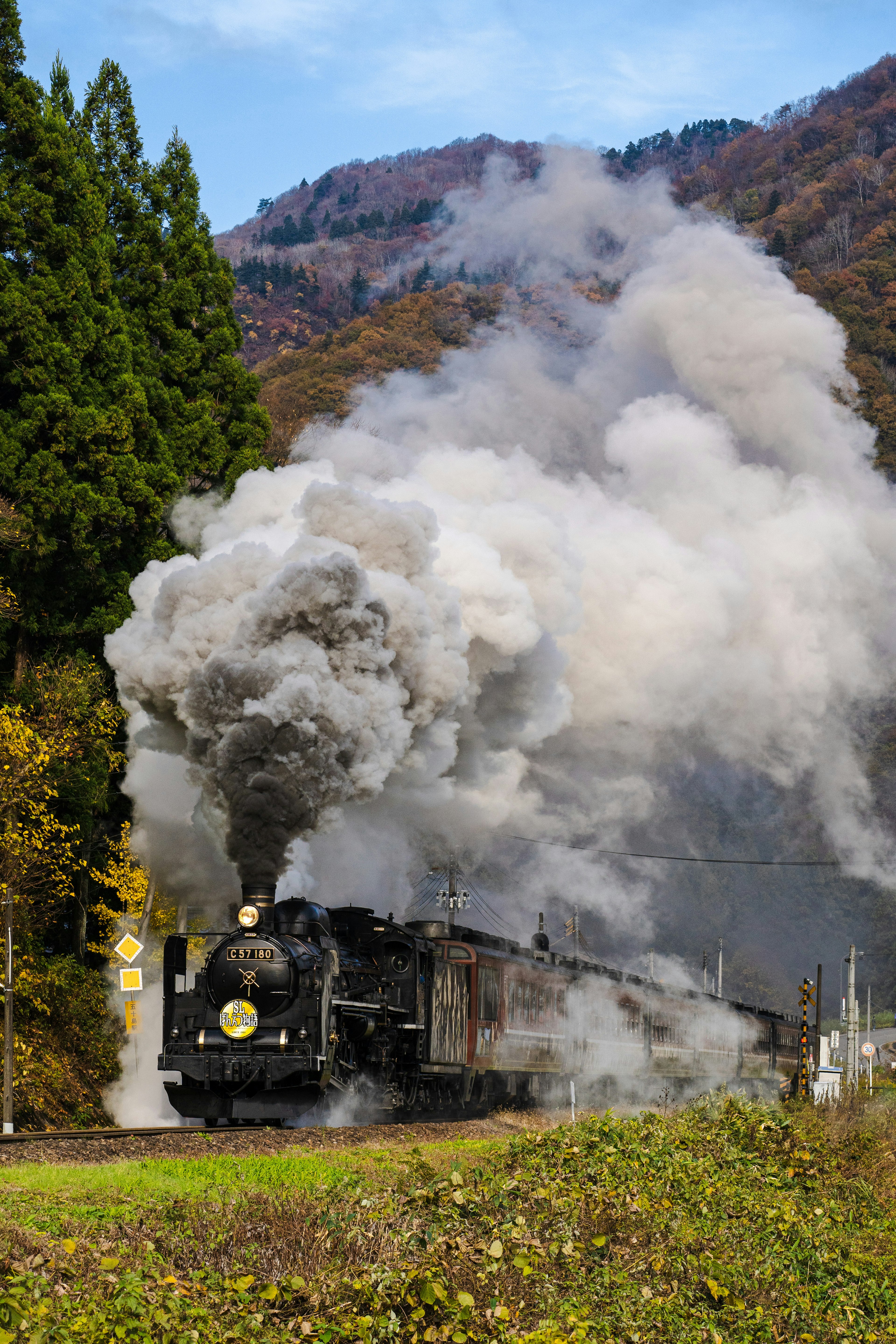 Locomotiva a vapore che emette fumi con montagne panoramiche sullo sfondo