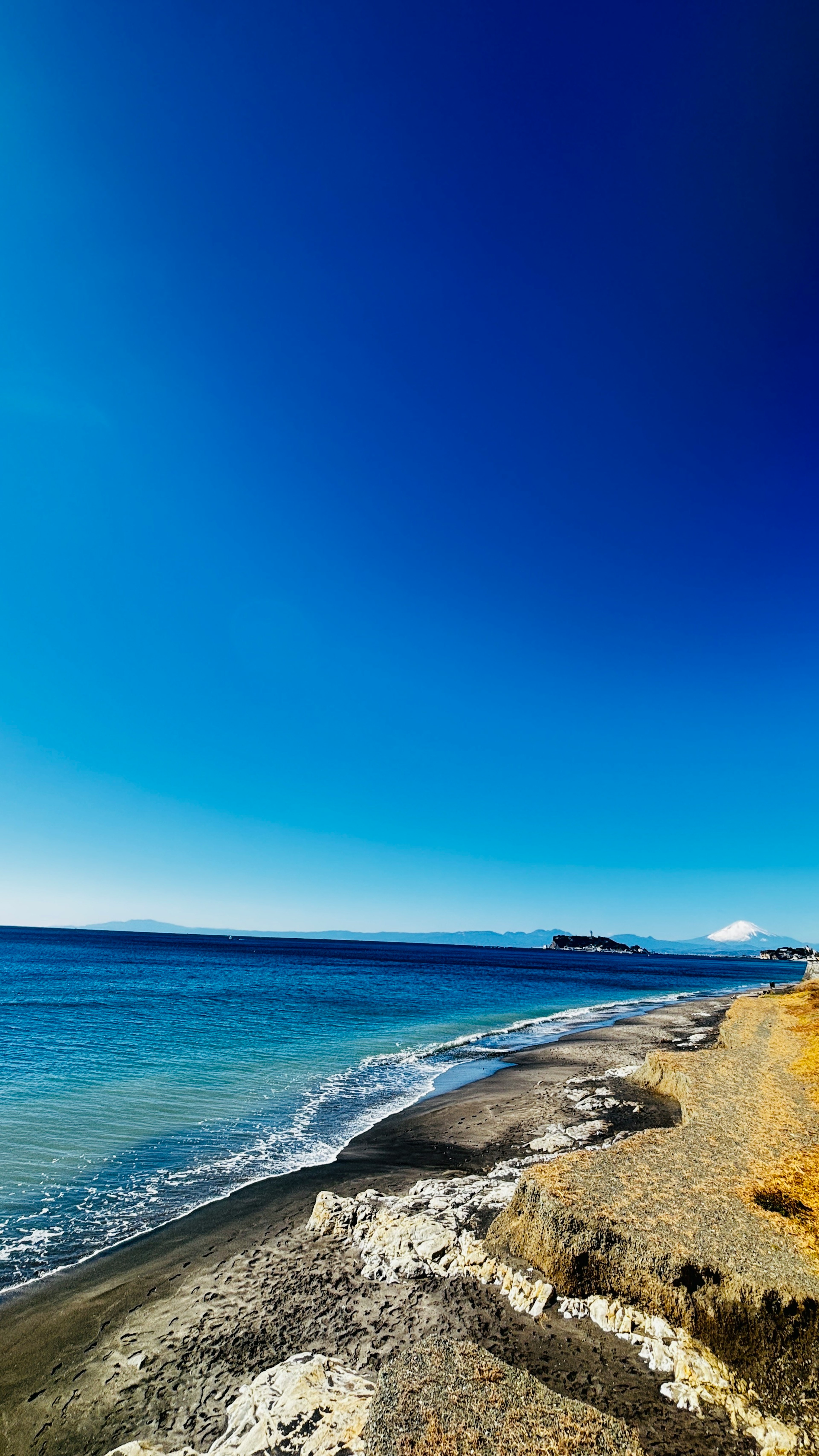 Pemandangan pantai dengan langit biru cerah dan laut tenang