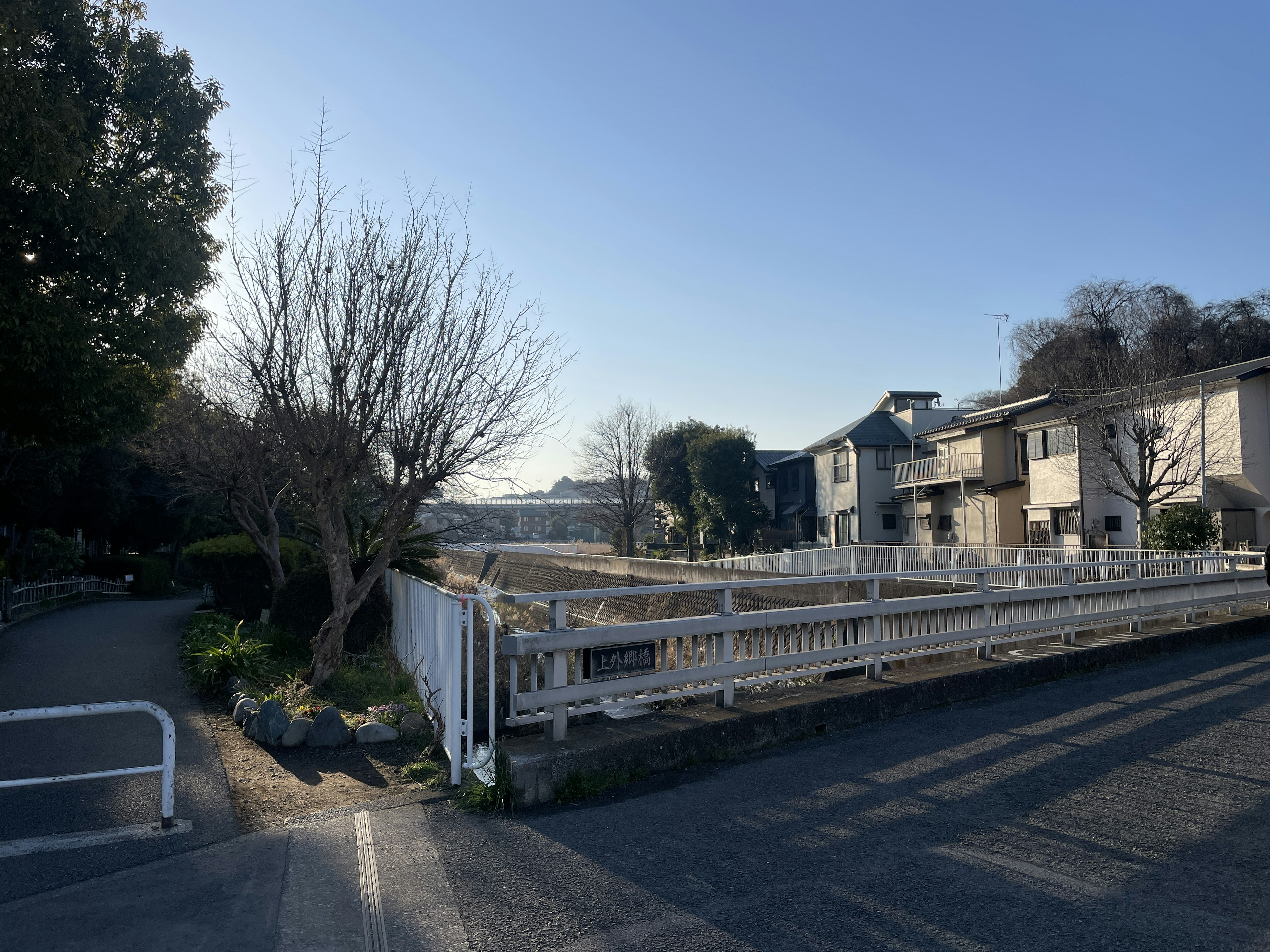 A landscape featuring a residential area and vacant lot under a clear blue sky