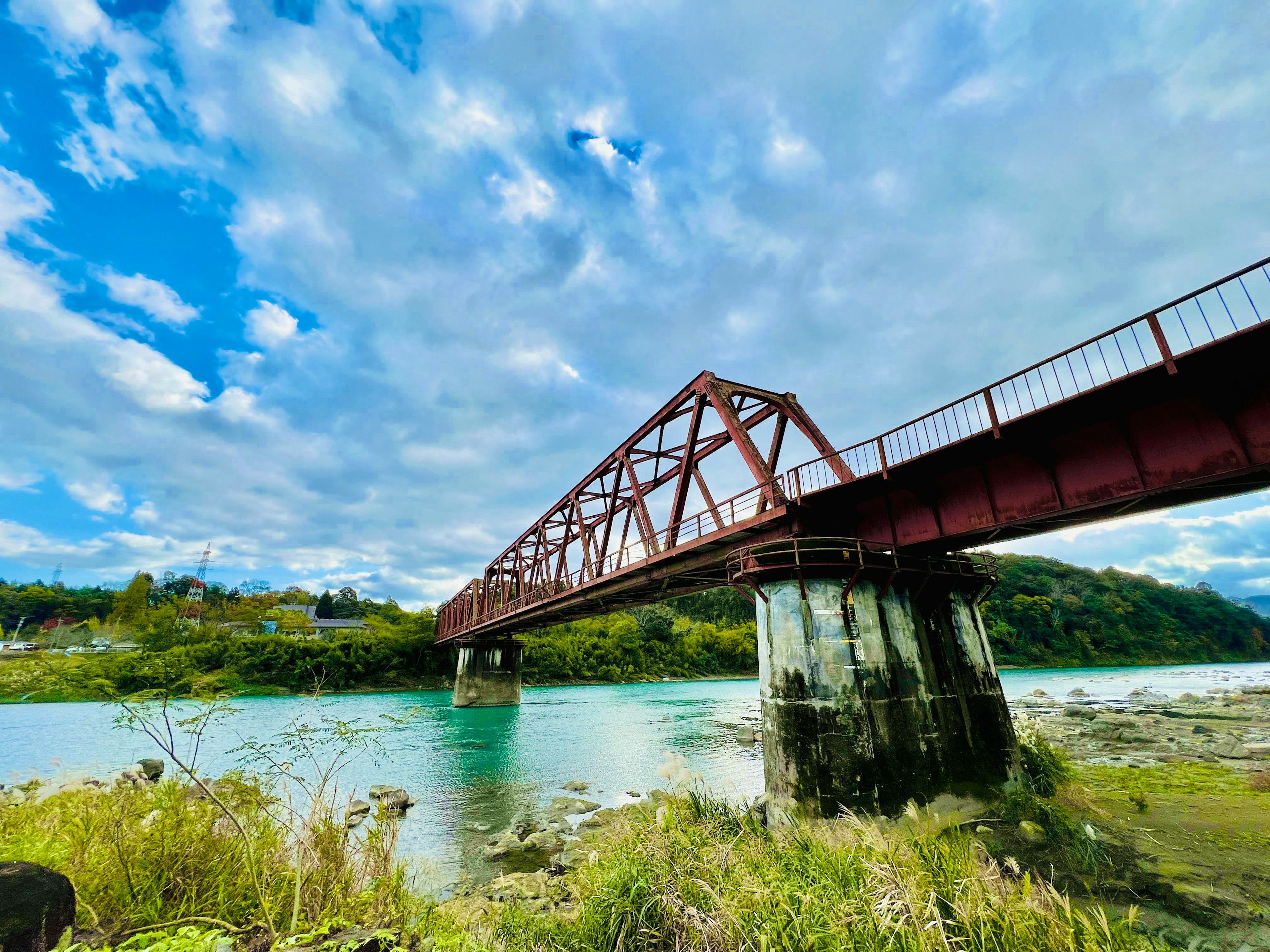 Pont en fer rouge s'étendant au-dessus d'une rivière sous un ciel bleu