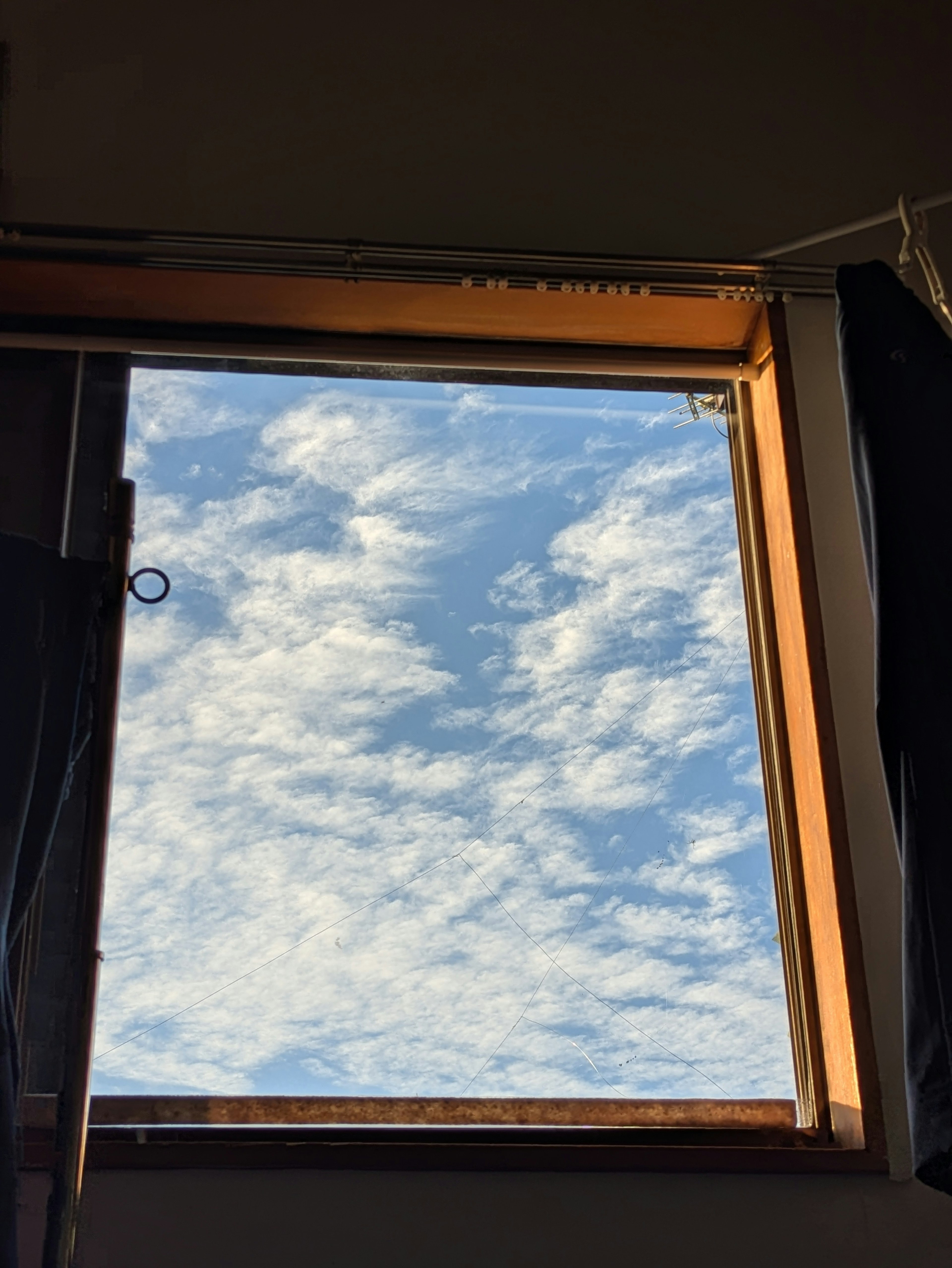 View of blue sky and white clouds through an open window