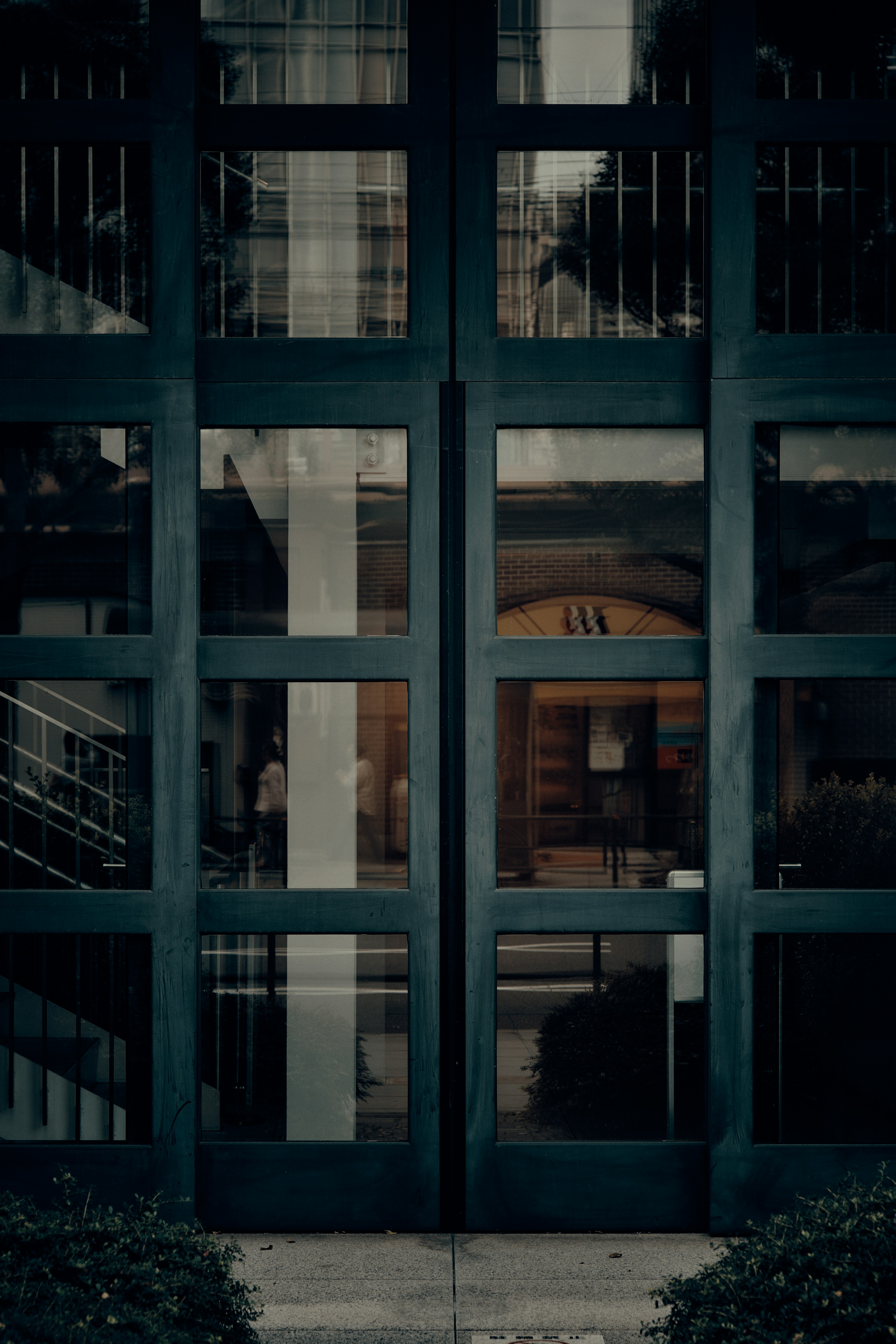 Modern building entrance with dark green glass doors and visible interior