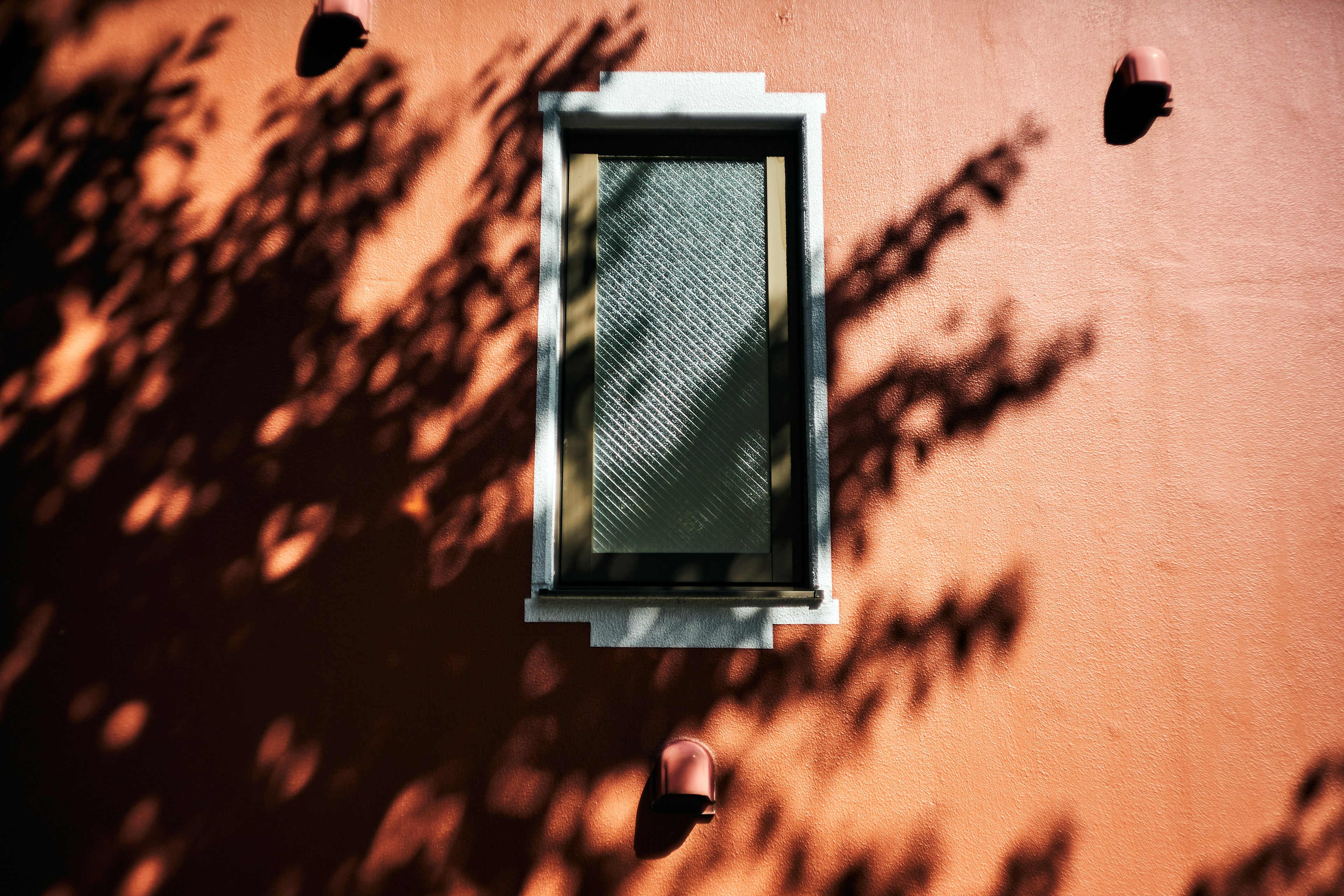 Ein Fenster an einer orangefarbenen Wand mit interessanten Schattierungen