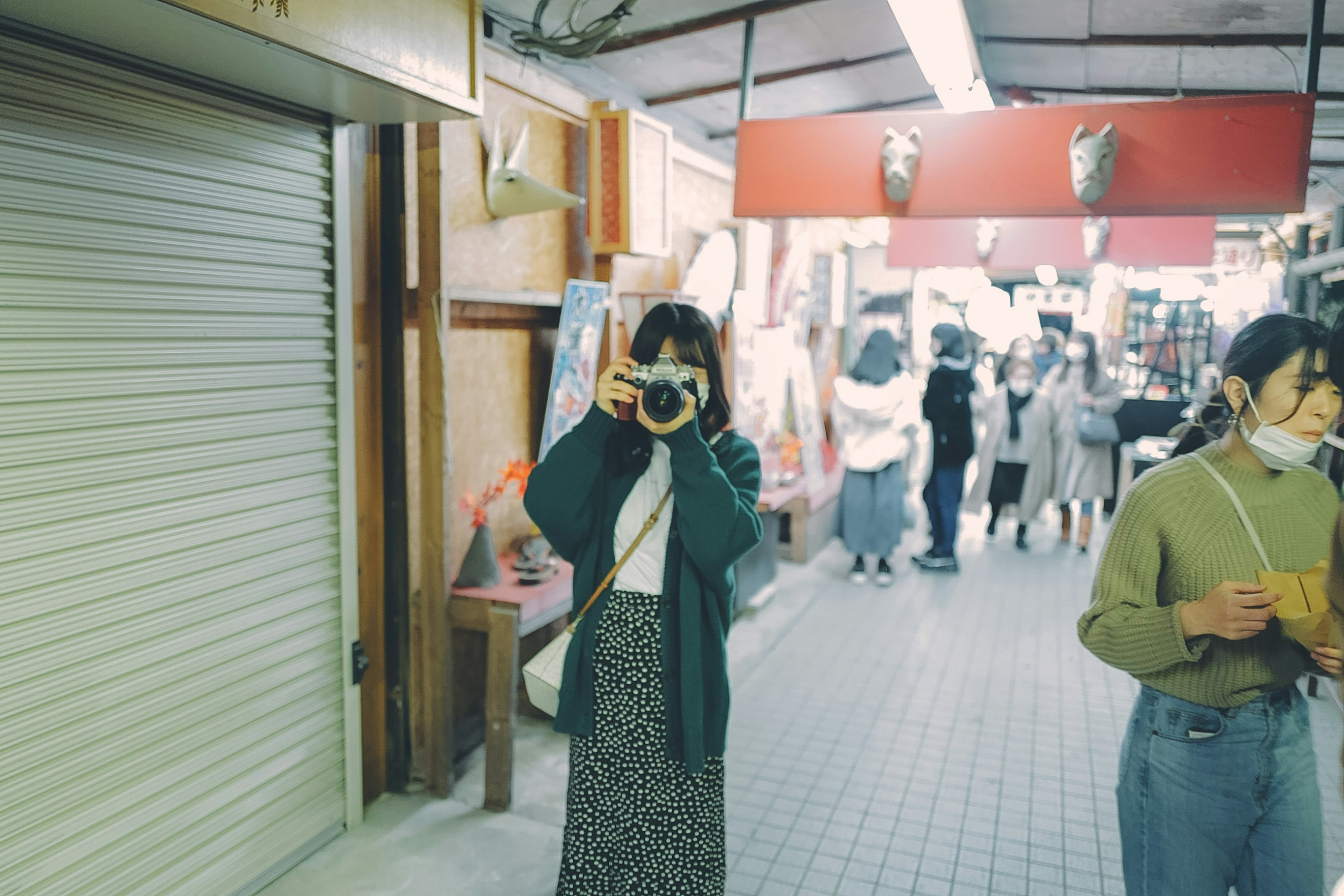 Woman holding a camera in a market with people in the background