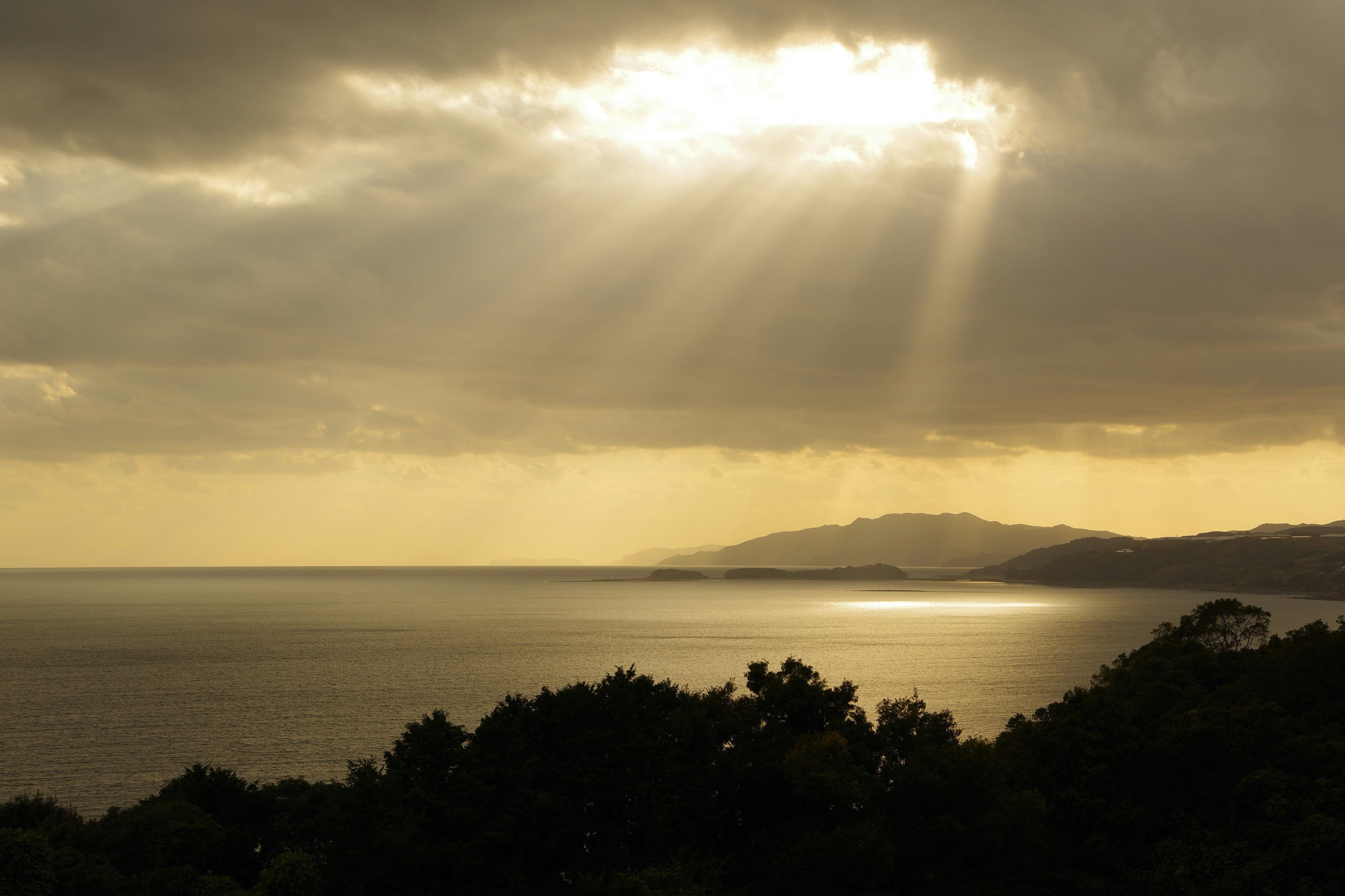 海と山が見える黄昏時の風景に光が差し込む