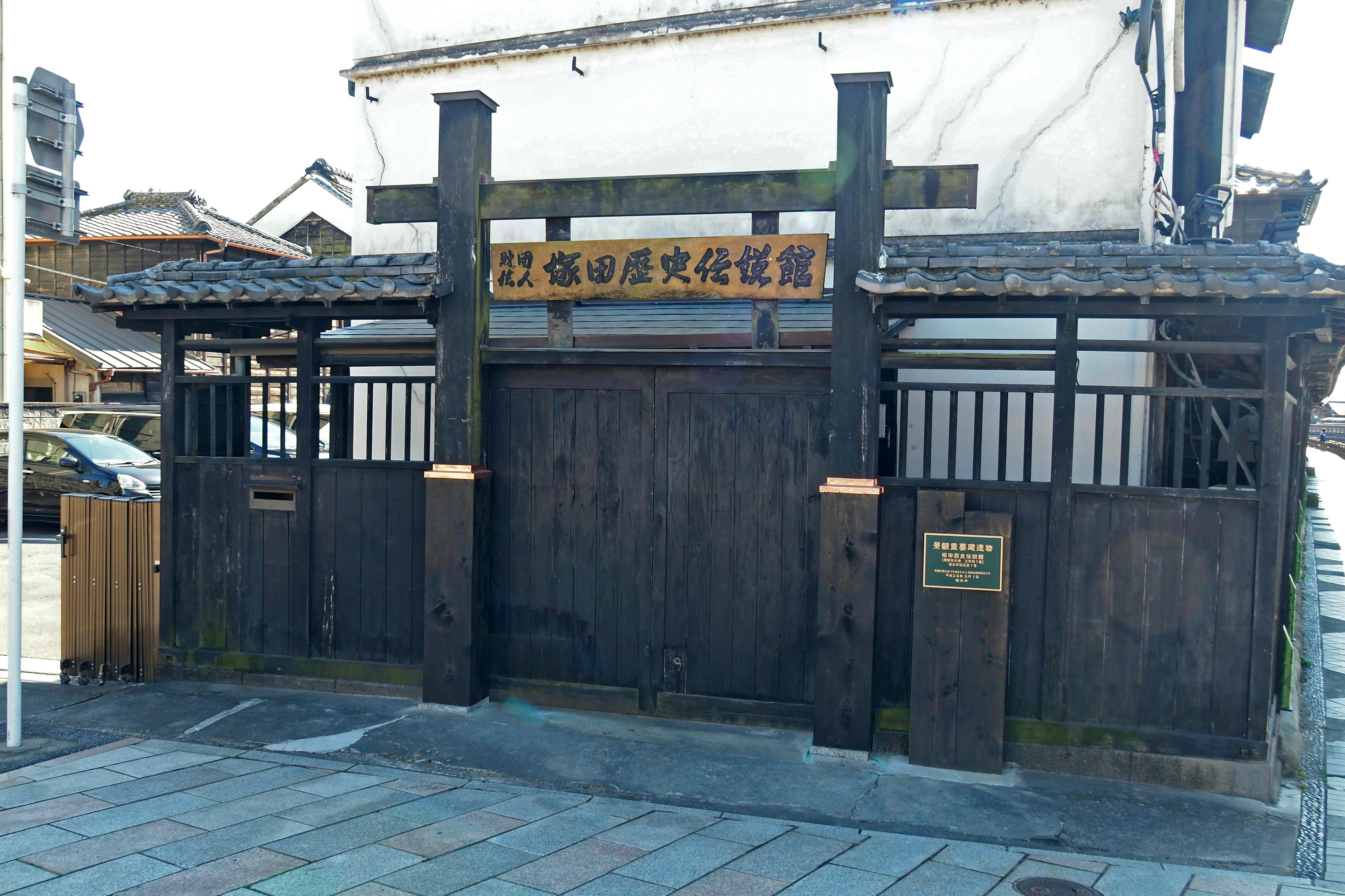 Exterior de un edificio japonés tradicional con puerta de madera negra y cartel