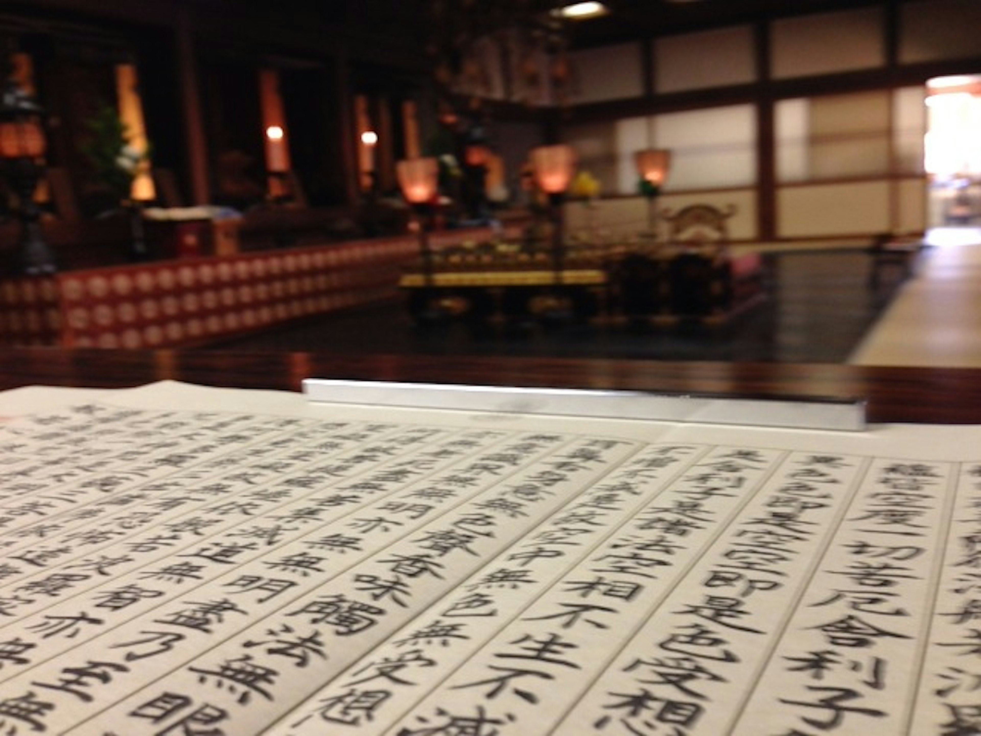 Calligraphy piece in the foreground with a traditional Japanese interior in the background