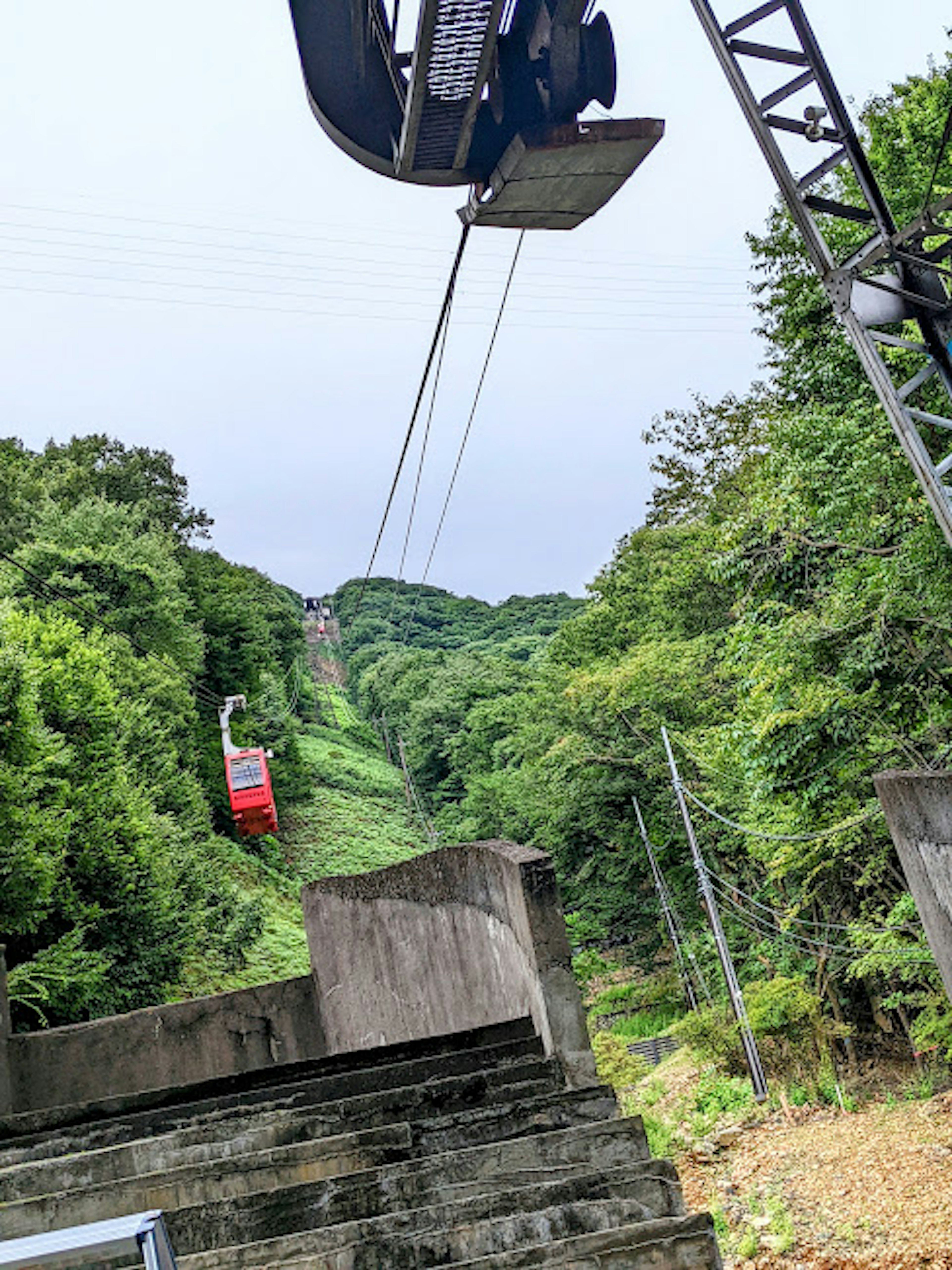 Teleférico rojo ascendiendo por montañas verdes