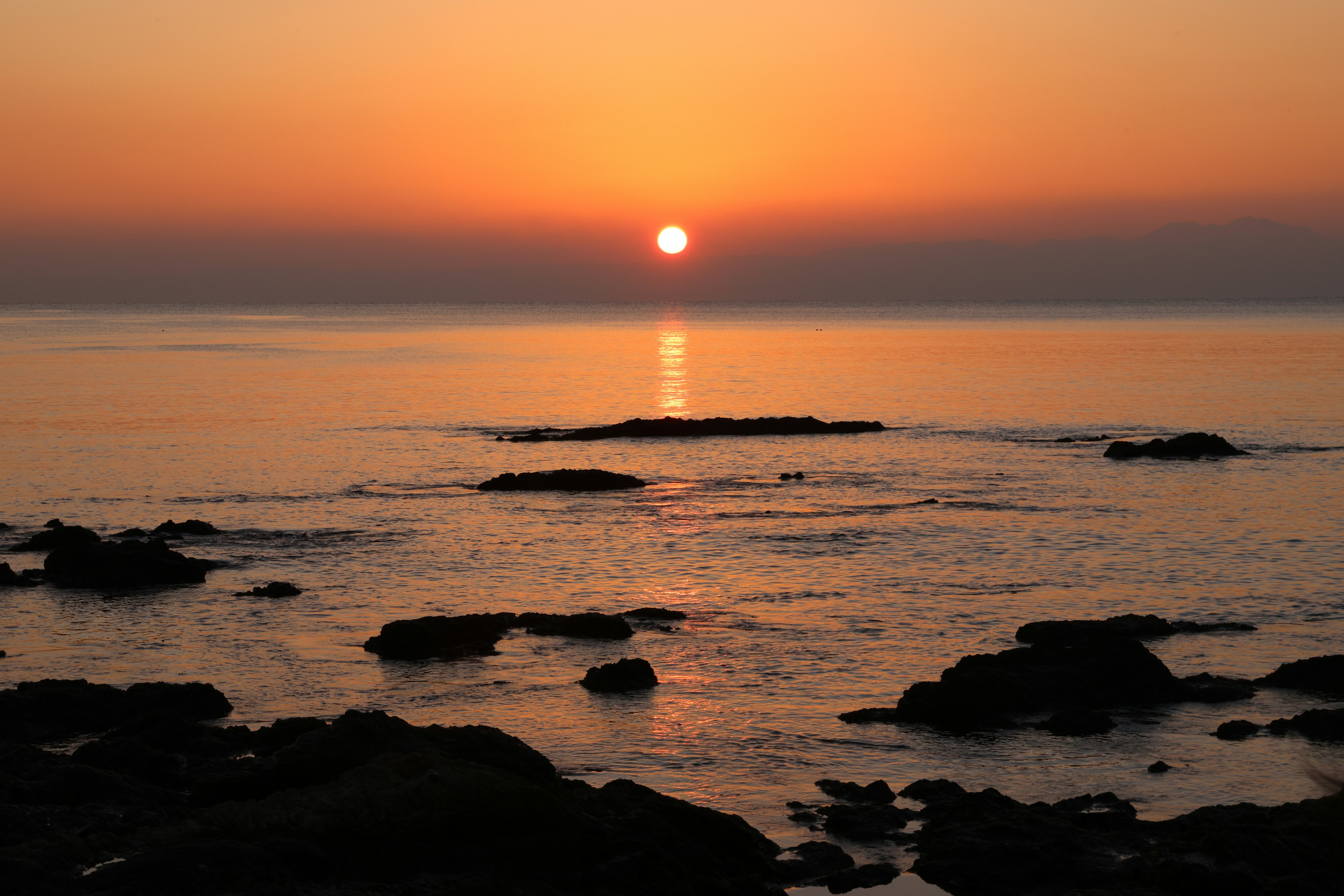 Schöne Meereslandschaft mit Sonnenuntergang über dem Ozean und silhouettierten Felsen